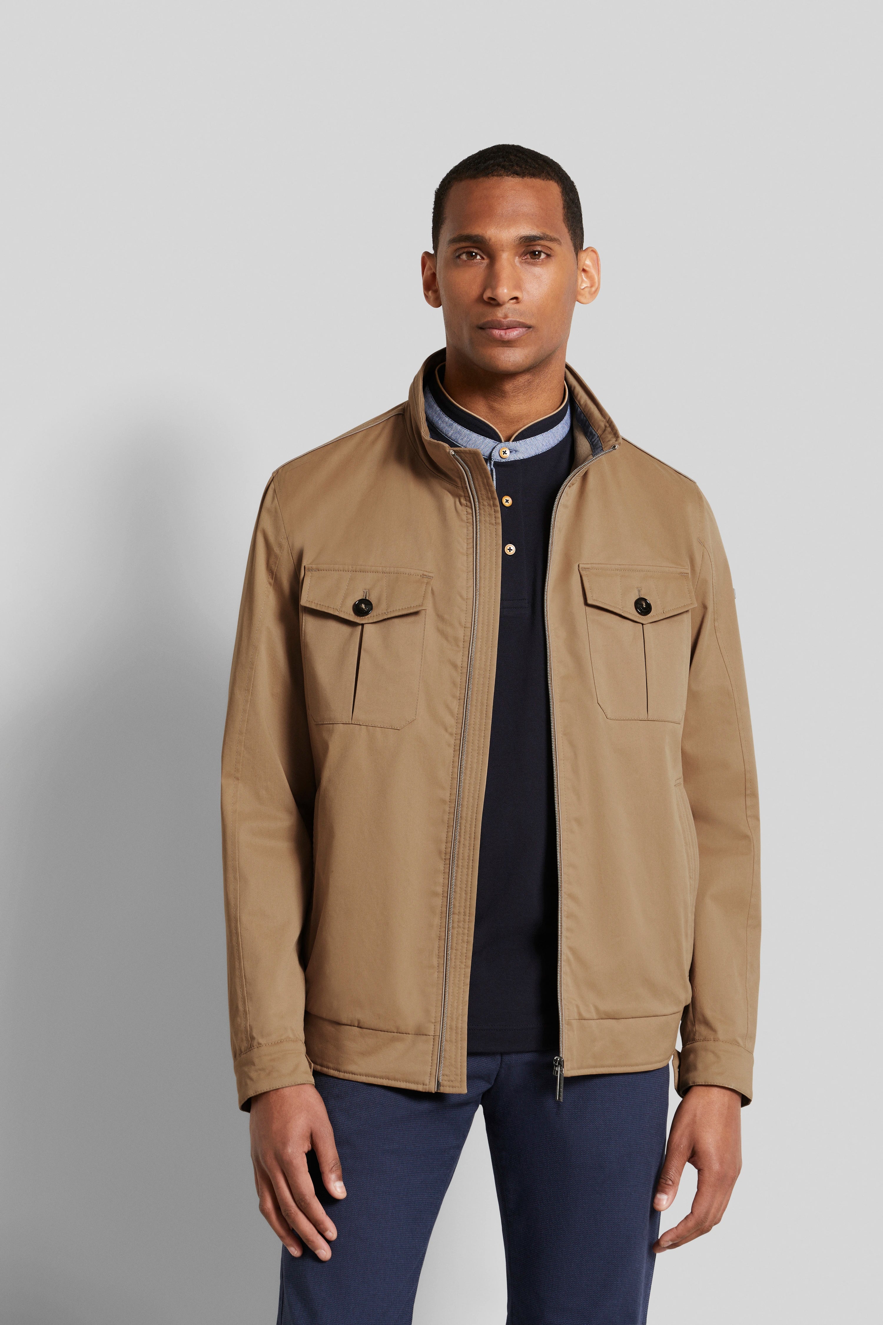 Bugatti Modelbild: Beige Jacke, navy Pullover, blaue Hose, entspanntes Posing.