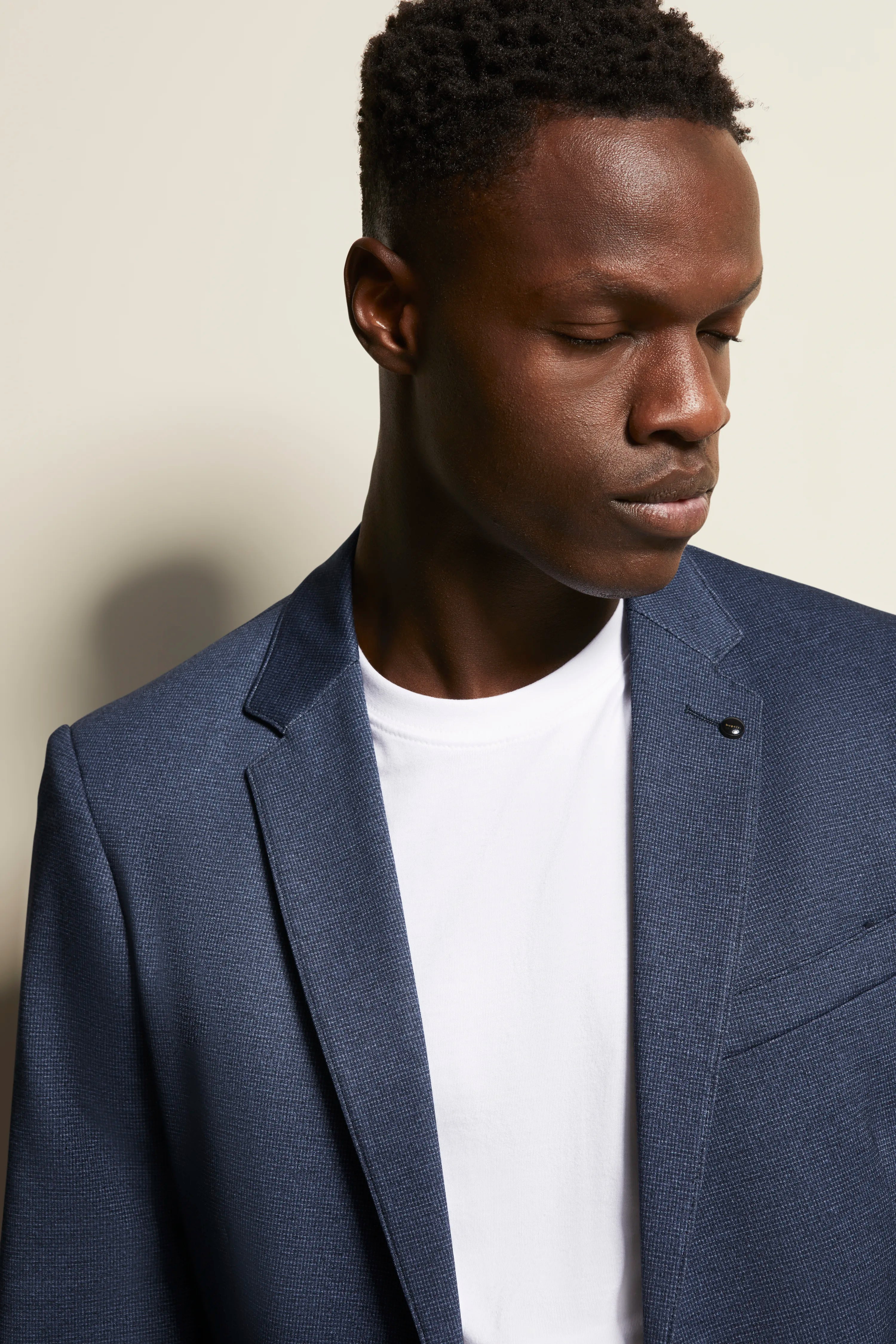 Model draagt blauwe bugatti blazer met wit T-shirt, elegante uitstraling.