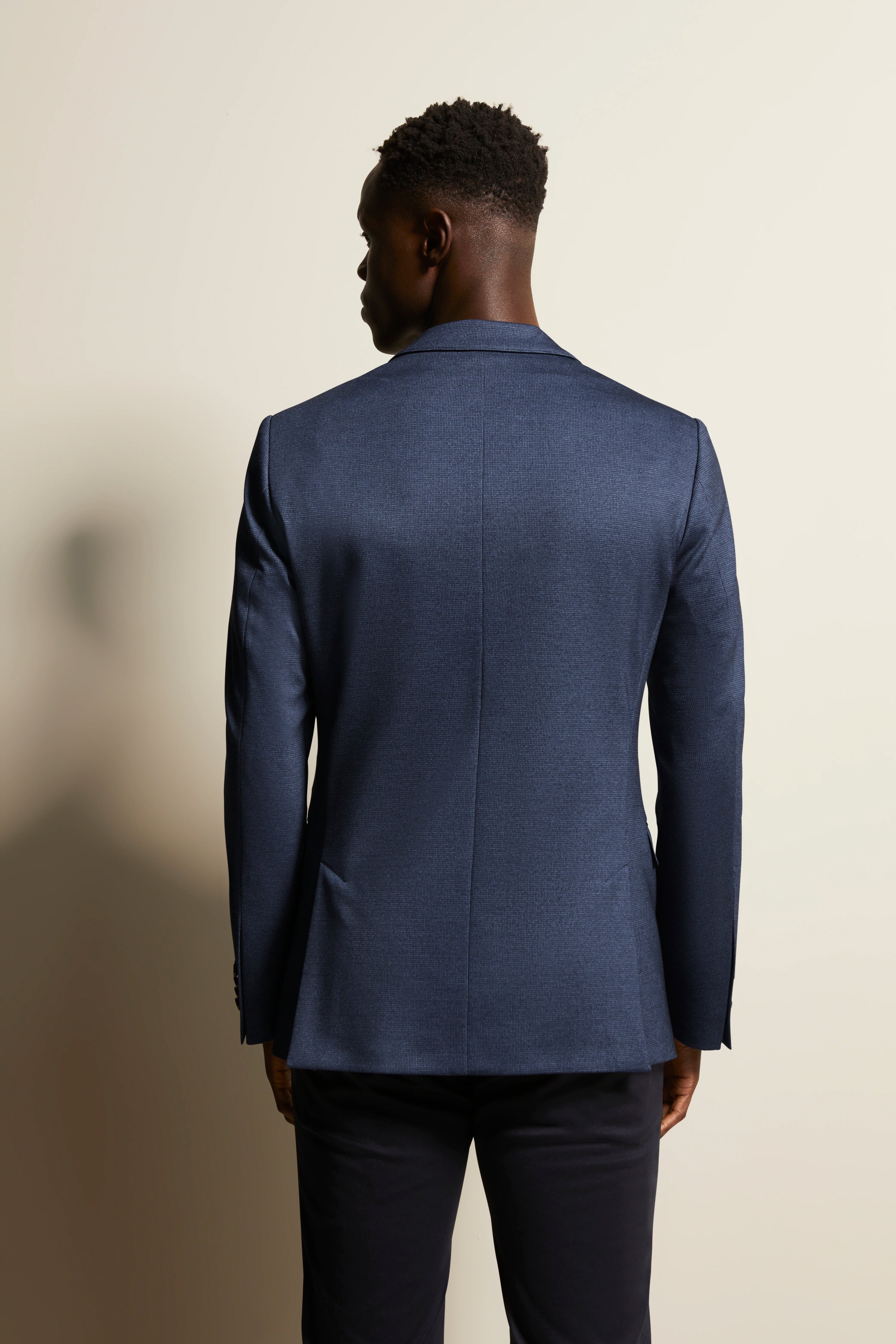 Achteraanzicht van een man in een elegant blauw bugatti colbert, modelafbeelding.