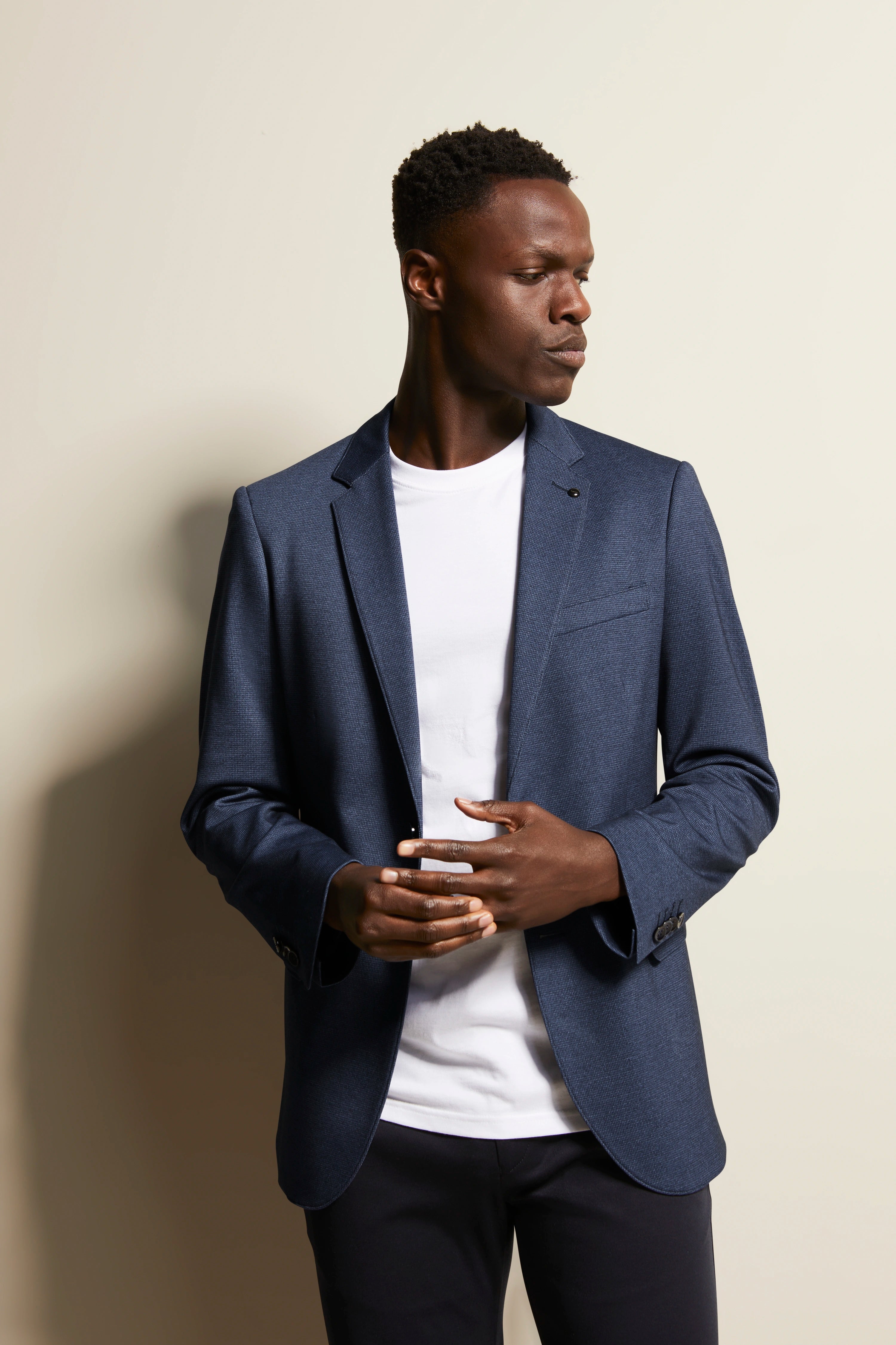 bugatti model, blauw colbert, wit shirt, zwarte broek, casual pose.