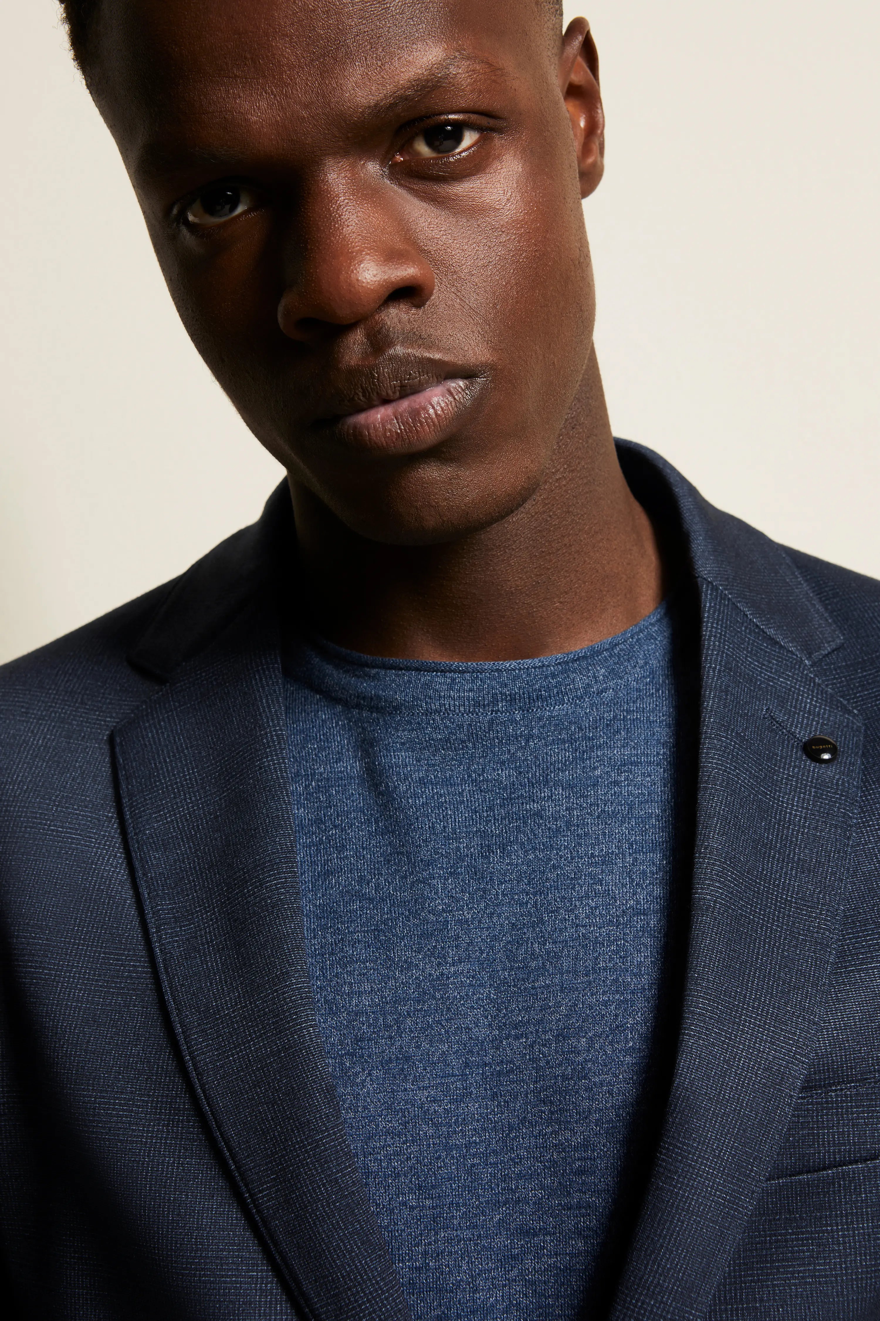 Model in marine bugatti blazer en blauw shirt, close-up, stijlvol en zelfverzekerd.