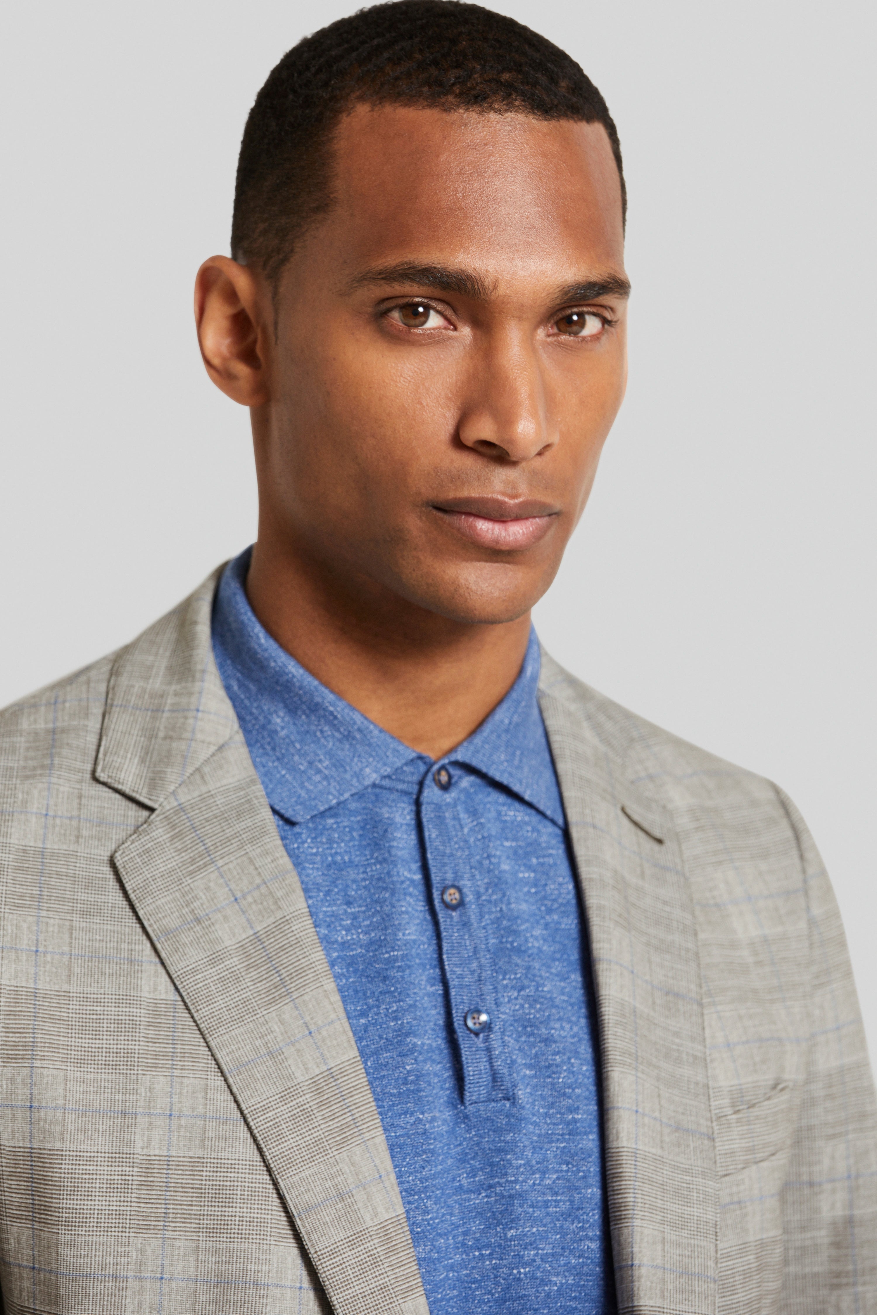 bugatti model: grijs geruit colbert, blauw poloshirt, elegante pose.