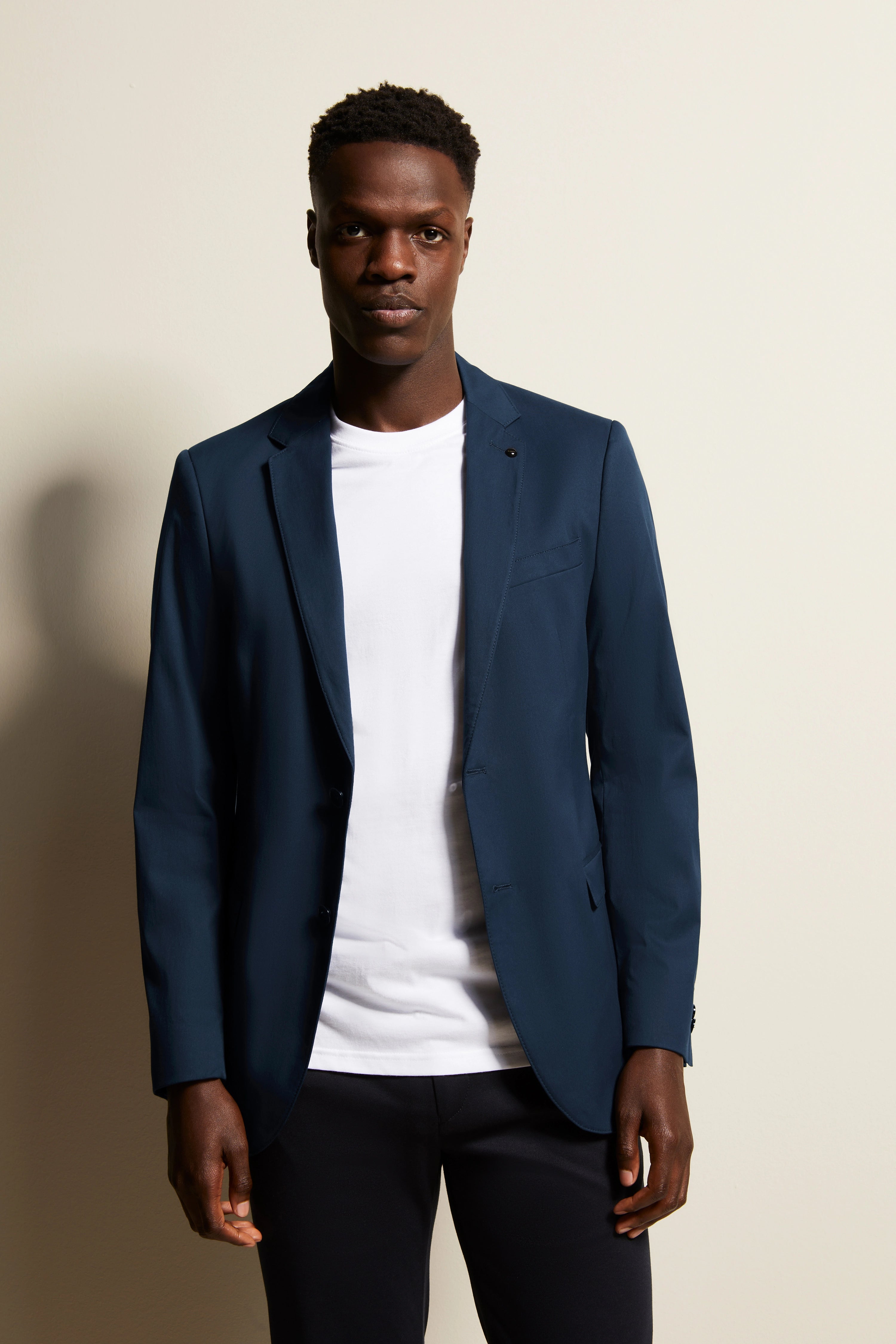 bugatti modelbeeld: Man in blauwe blazer en wit T-shirt, nonchalante pose, stijlvol en tijdloos.
