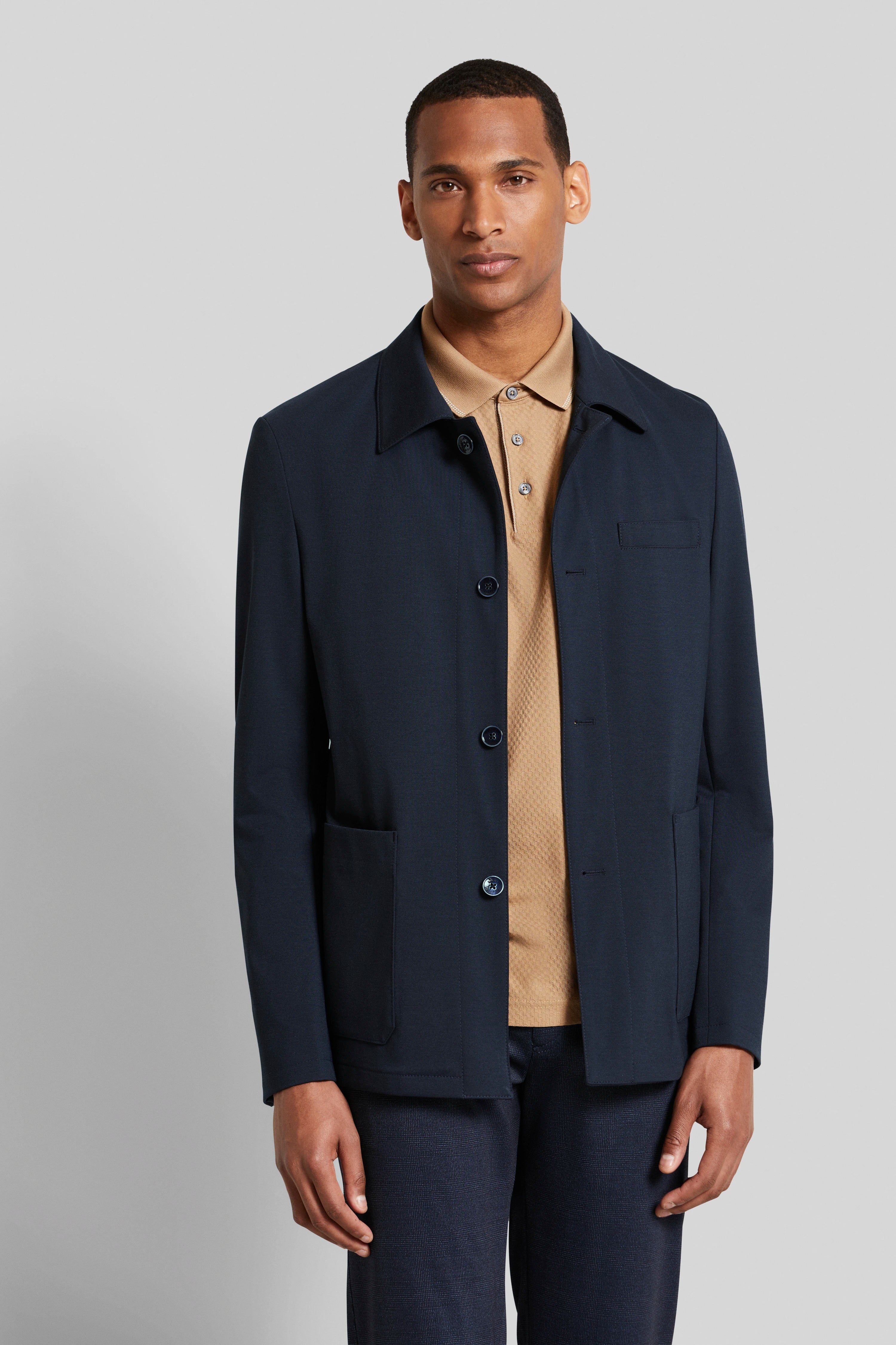 Model in navy bugatti jacket, beige polo, dark pants, relaxed pose.