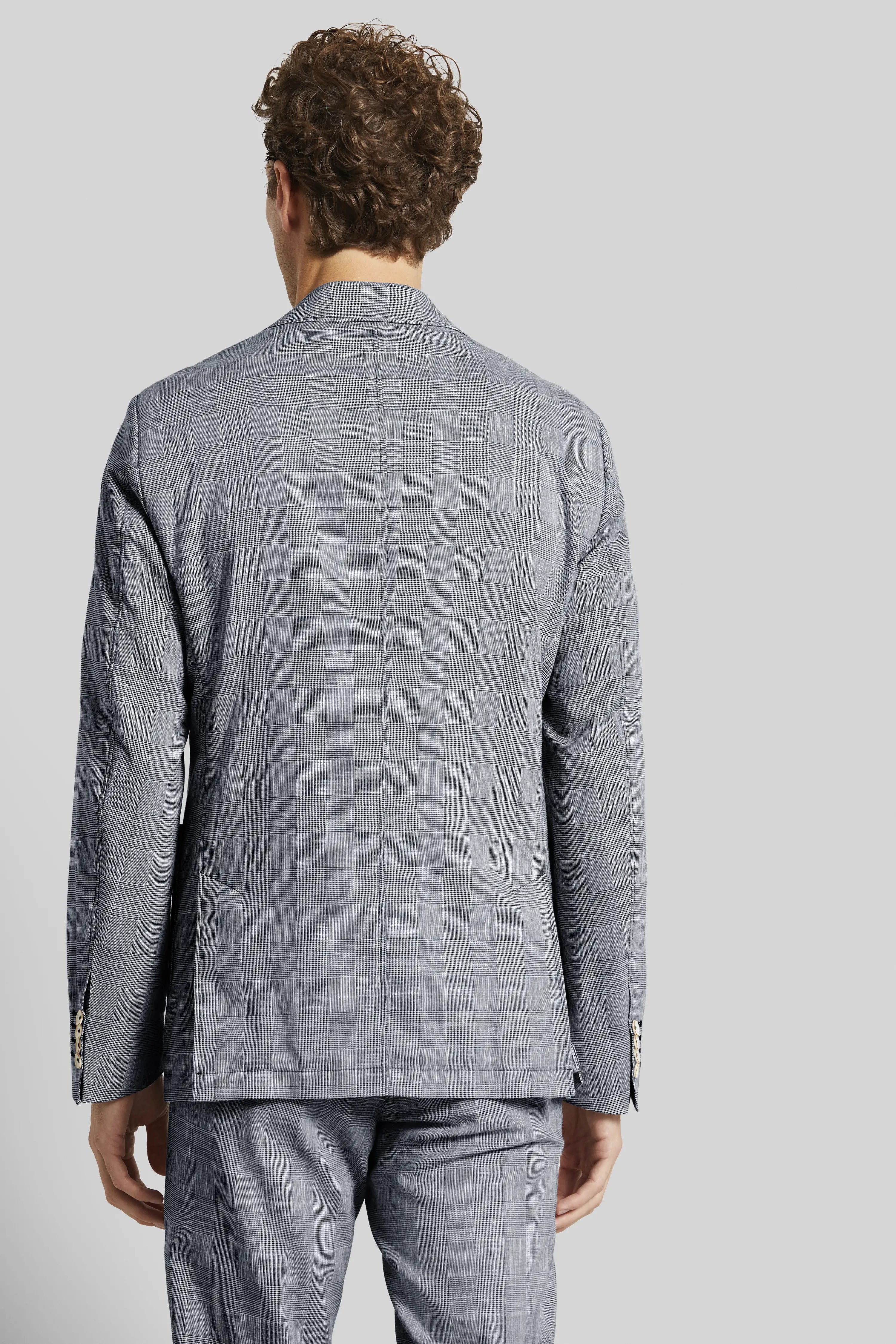Men's grey checkered suit, rear view, model stands relaxed in bugatti style.
