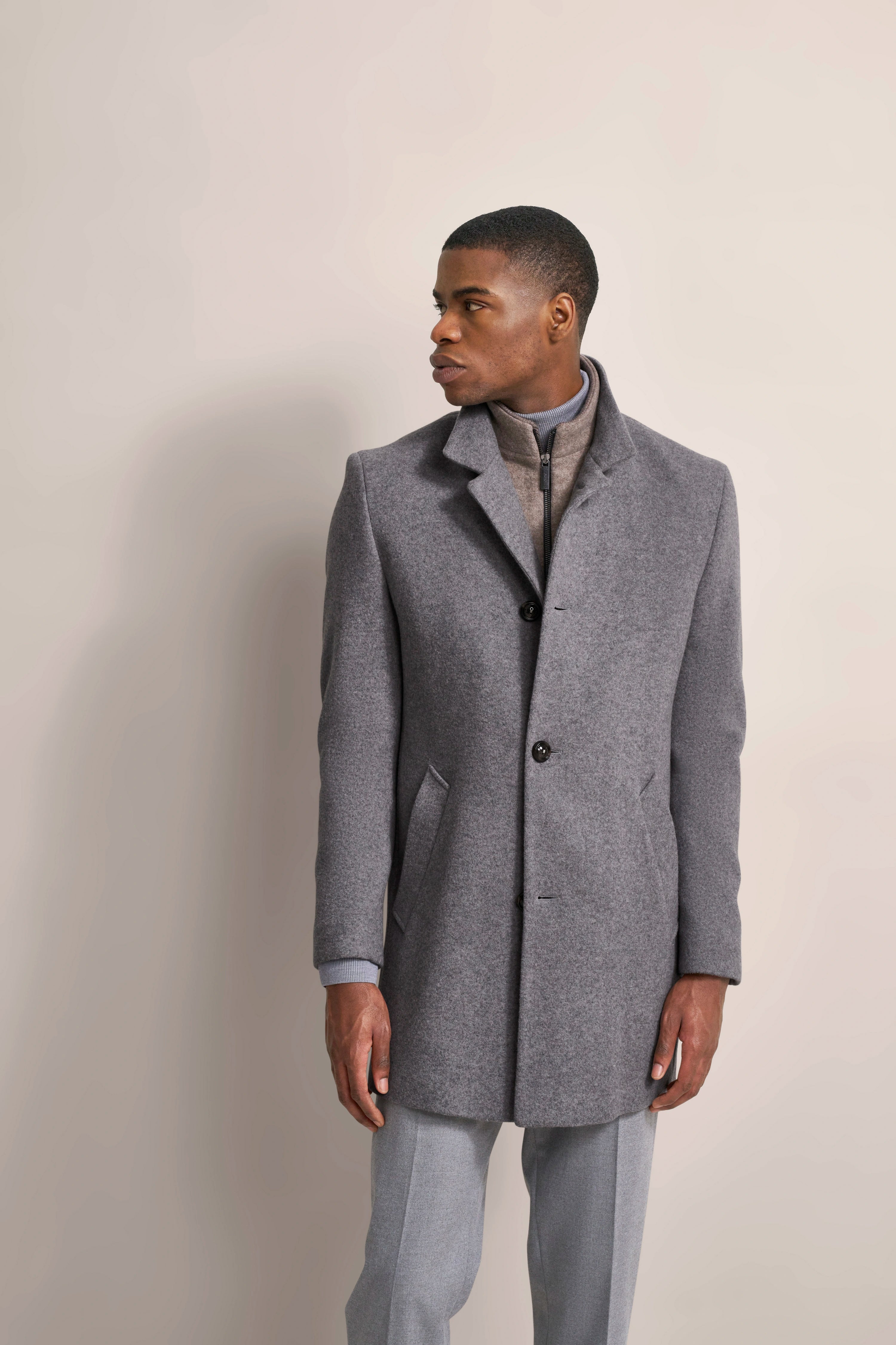 Gray bugatti coat with lapels, beige stand-up collar underneath, model looking sideways.