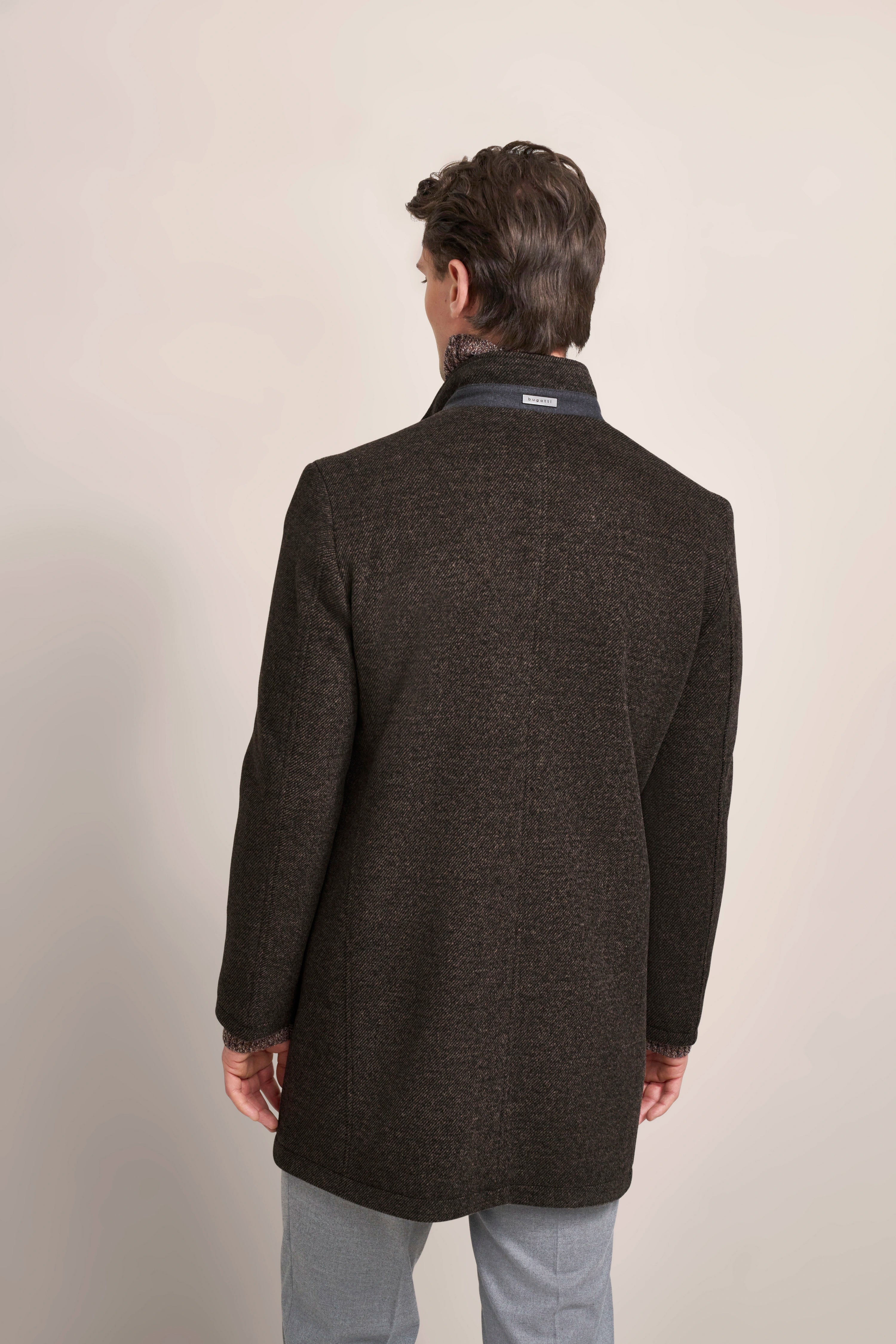 bugatti coat in dark brown, back view, worn by model in gray pants, casual pose.