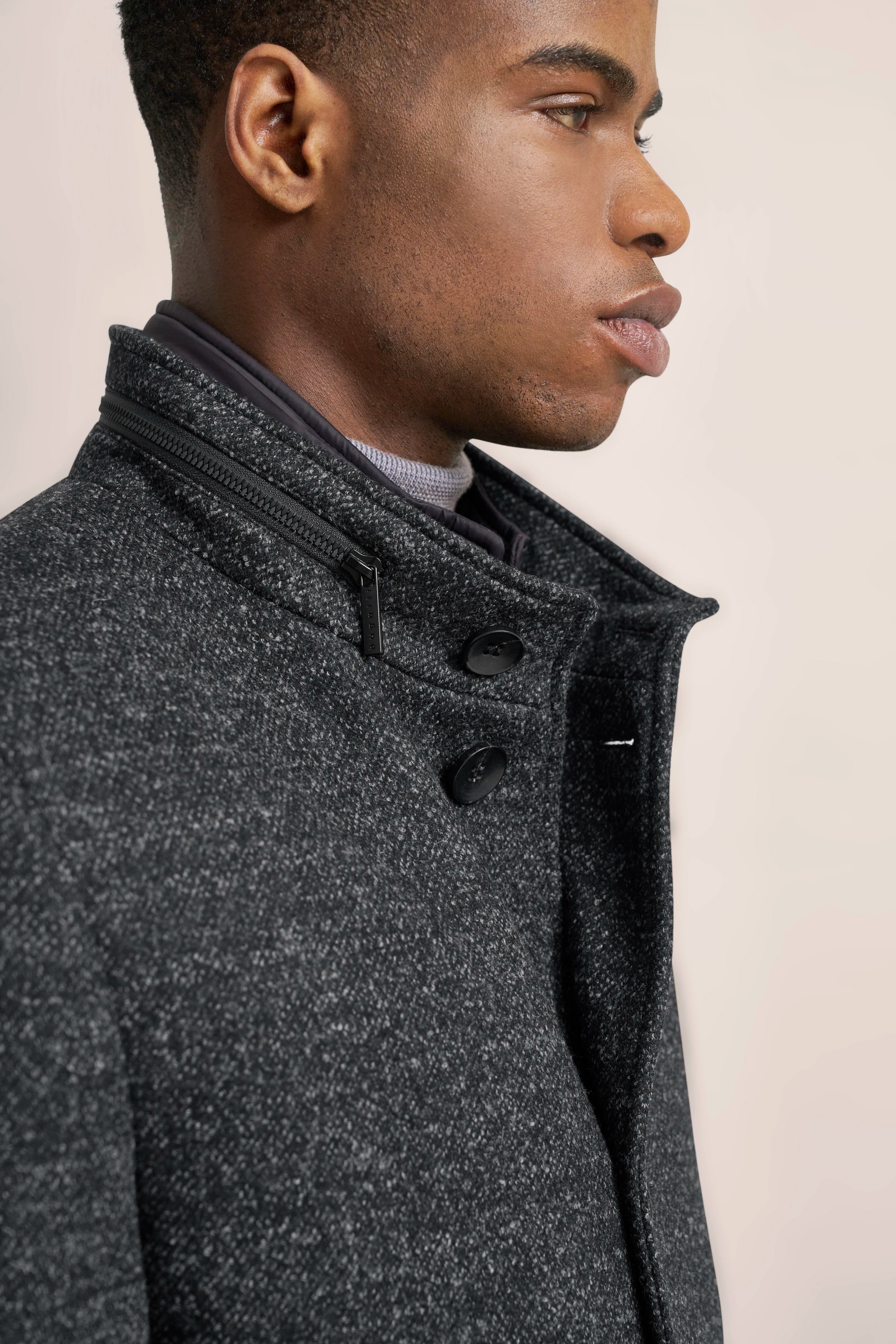 Close-up of a man in a grey textured bugatti coat with stand-up collar and button placket.