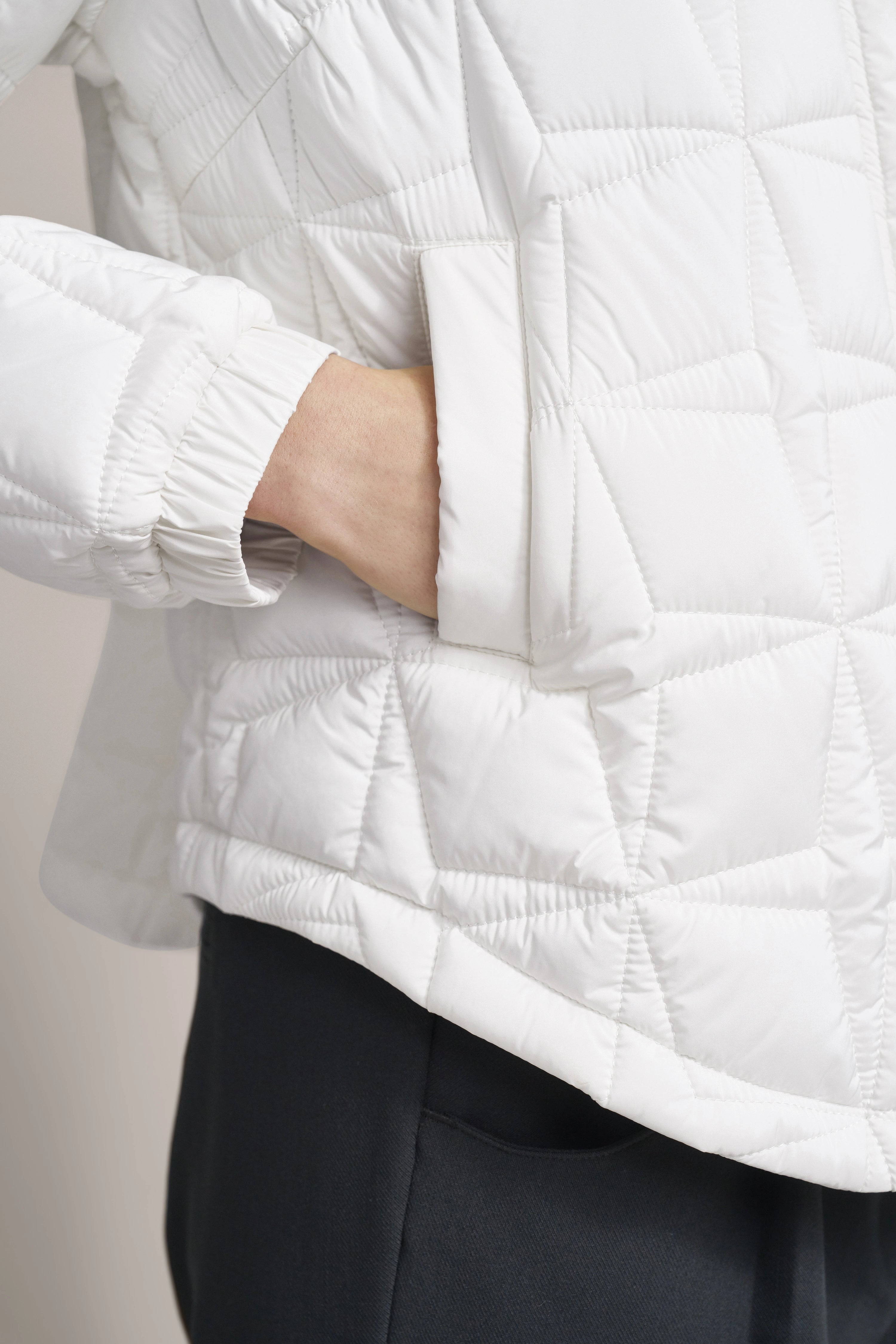 Weiße Steppjacke von bugatti, Nahaufnahme, geometrisches Muster, Hand in Tasche, legeres Bild.