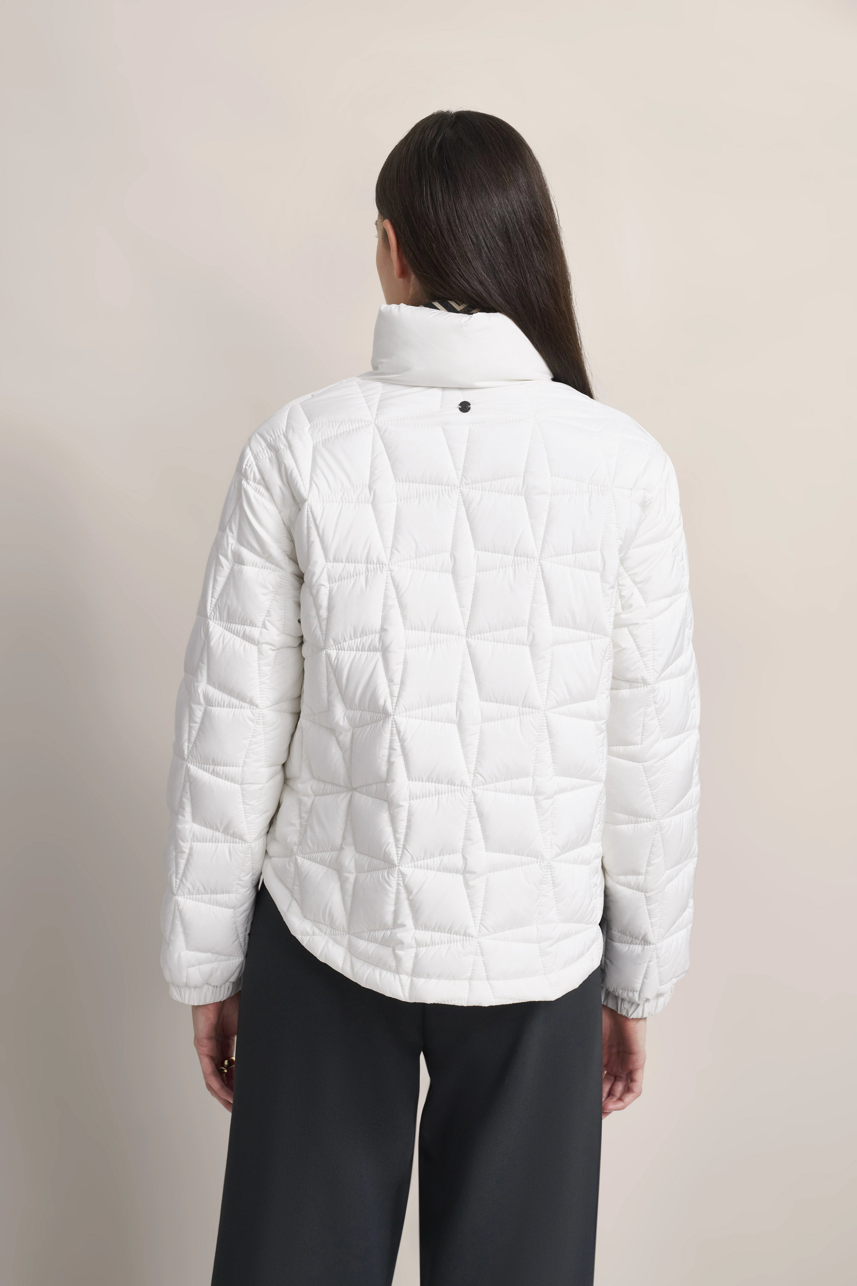 White quilted jacket by bugatti, back view, black pants, casual pose.