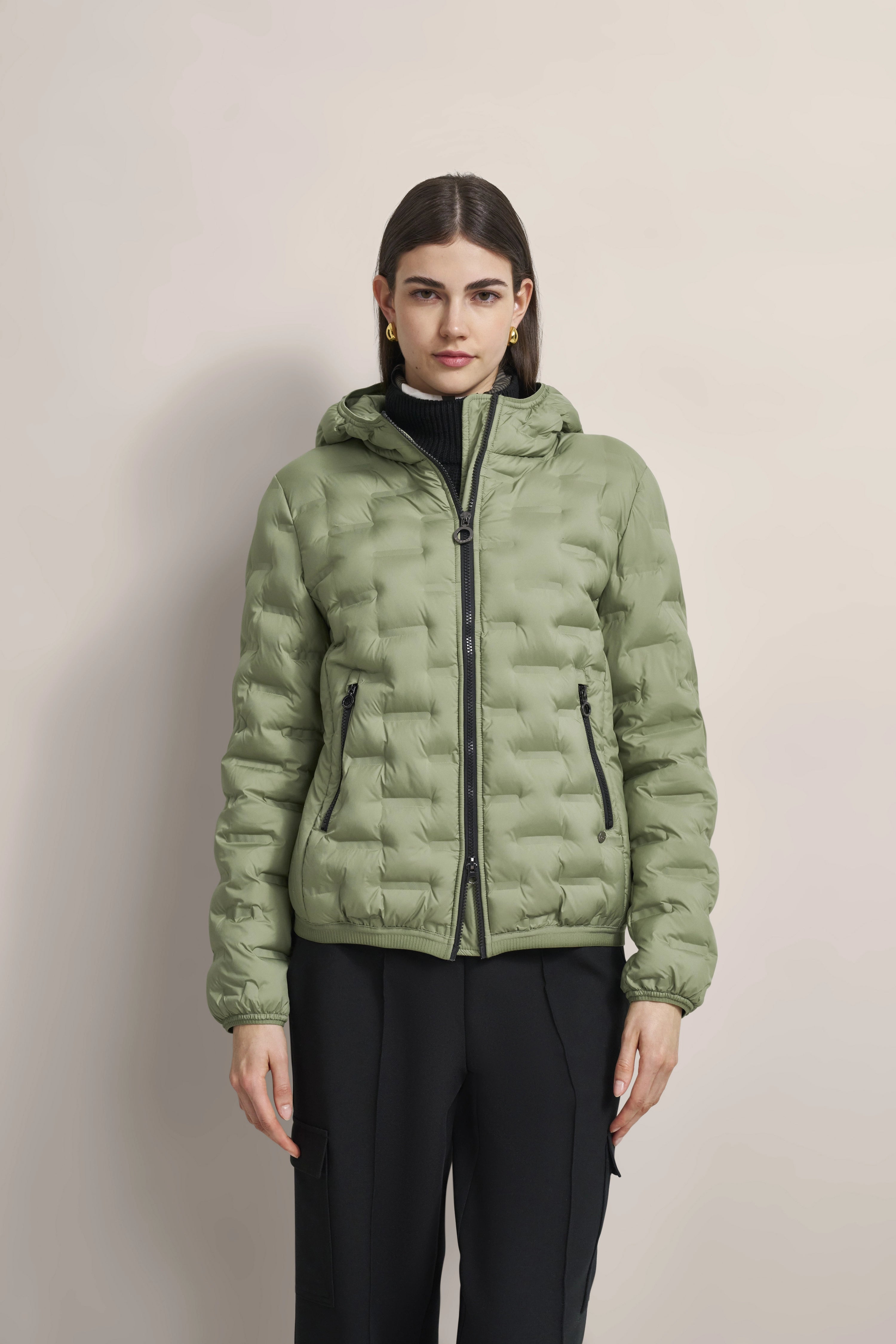Woman in bugatti puffer jacket, light green, with hood, model image, standing frontally, black pants.