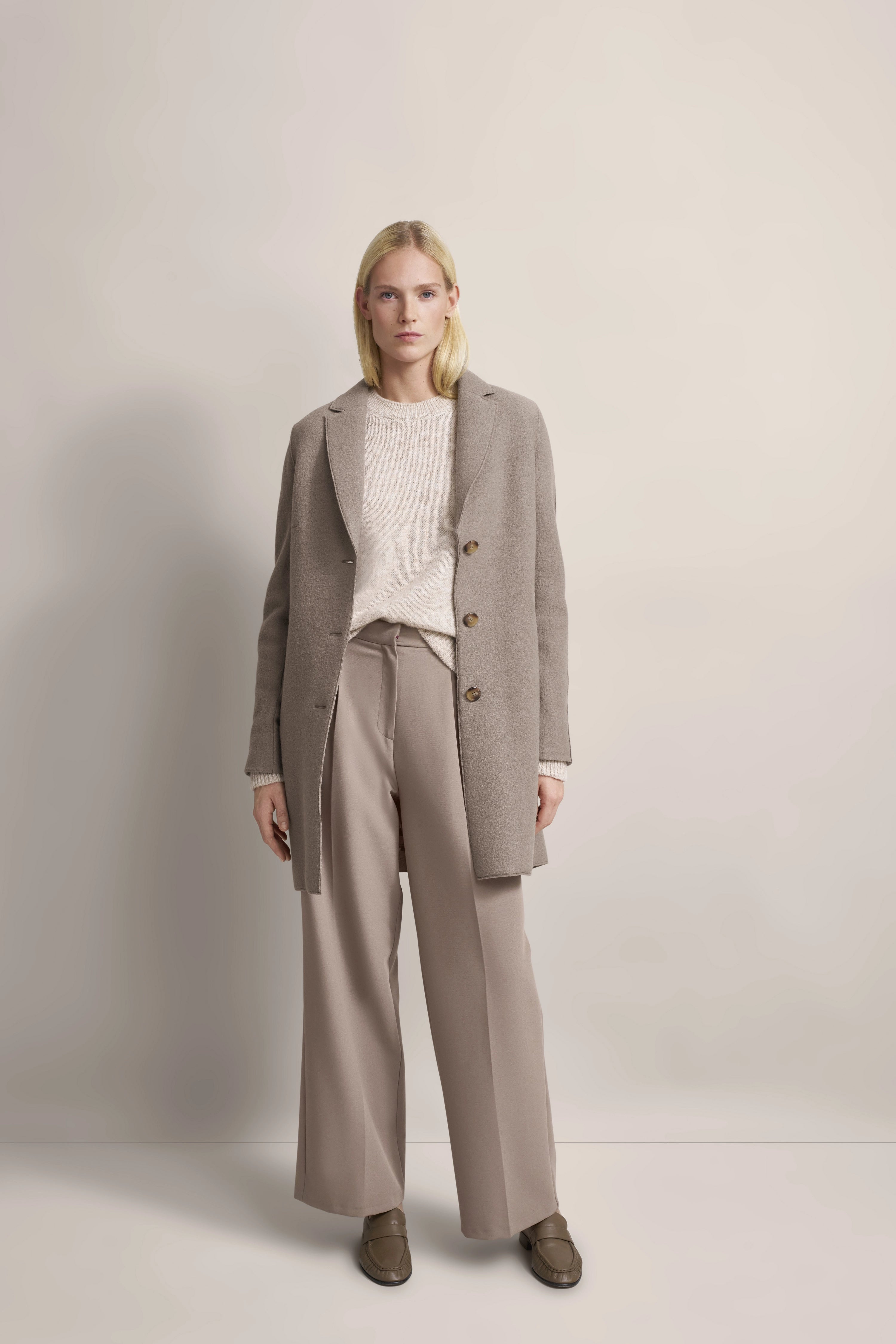 Damenmantel beige, Rückansicht auf Model. Lässig-elegantes Design von bugatti, inspiriert von italienischer Gelassenheit.