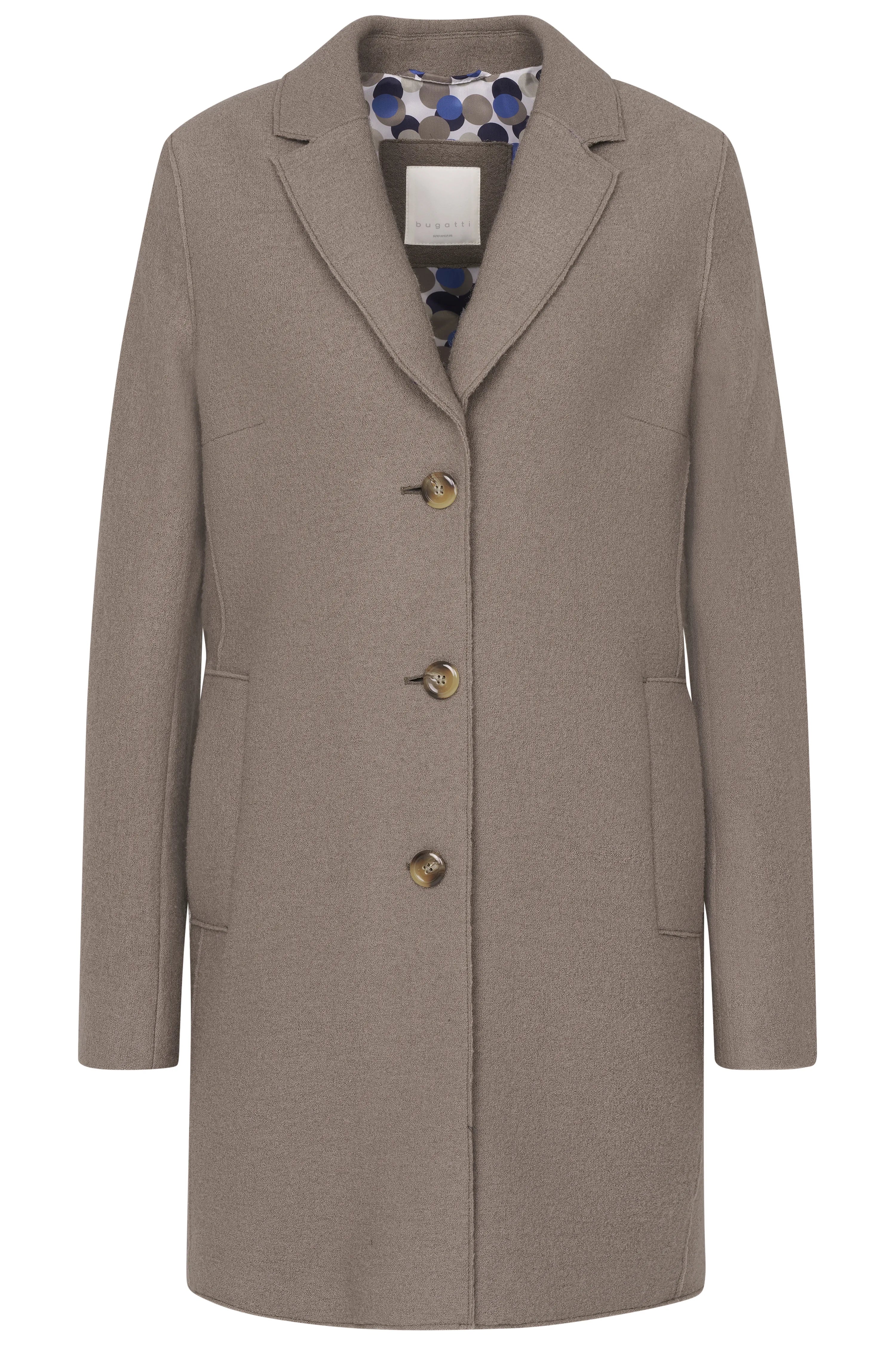 Model trägt beige Mantel, cremefarbenen Pullover, weite Hose. Stehendes Posing.