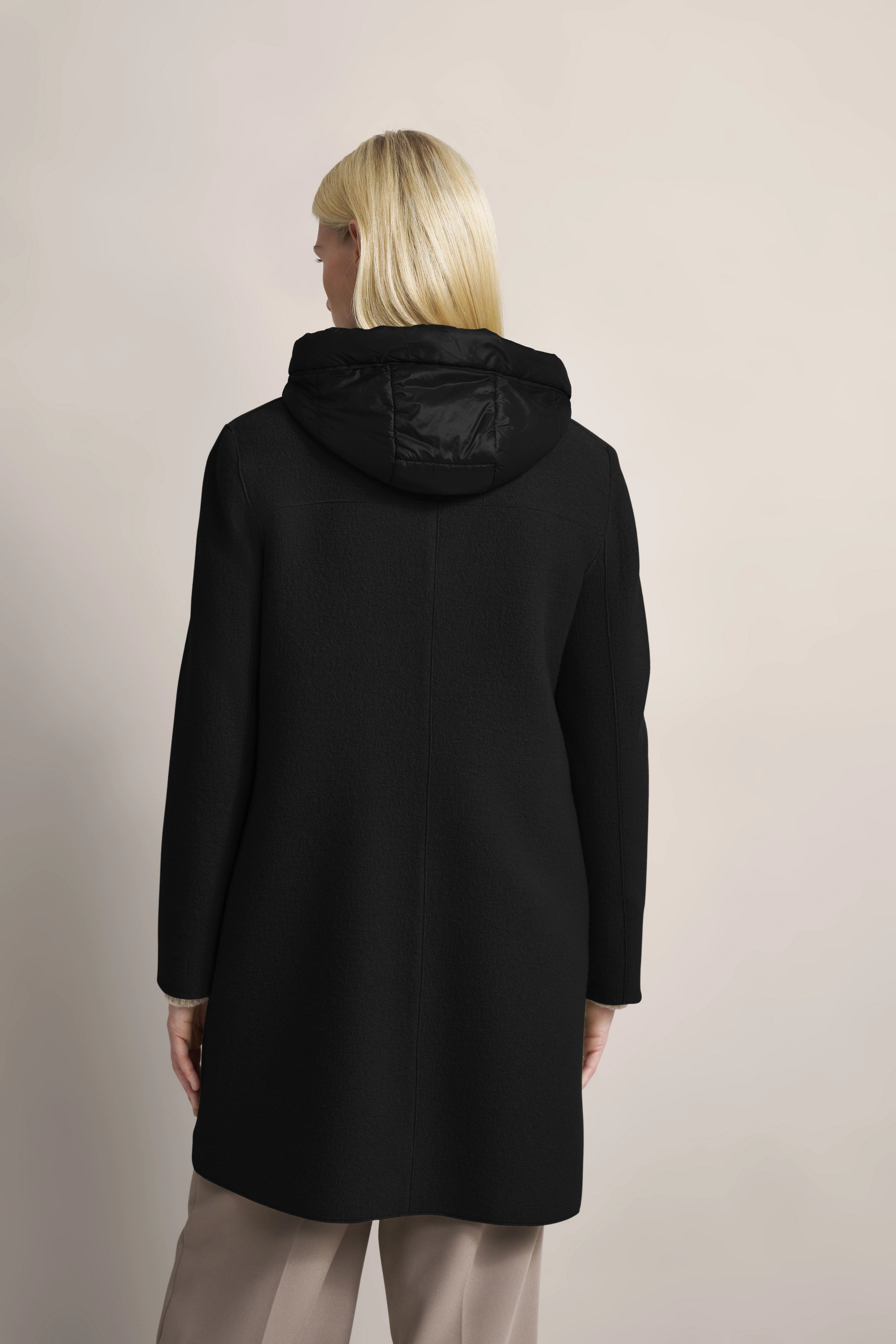 Black bugatti coat with hood, back view, beige pants.