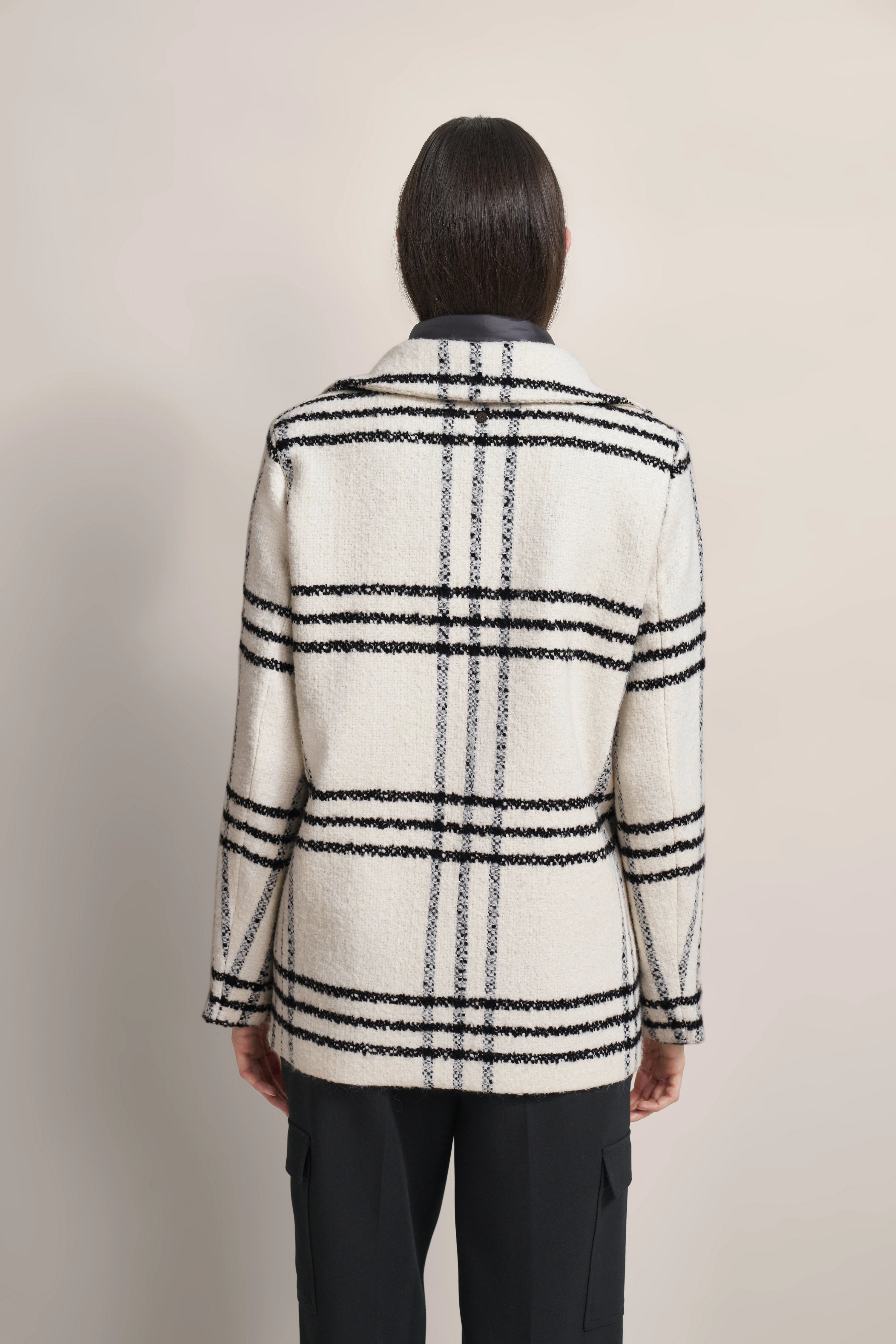 Rückansicht eines Models in weißem bugatti Karomantel, schwarzer Hose, entspanntes Posing.