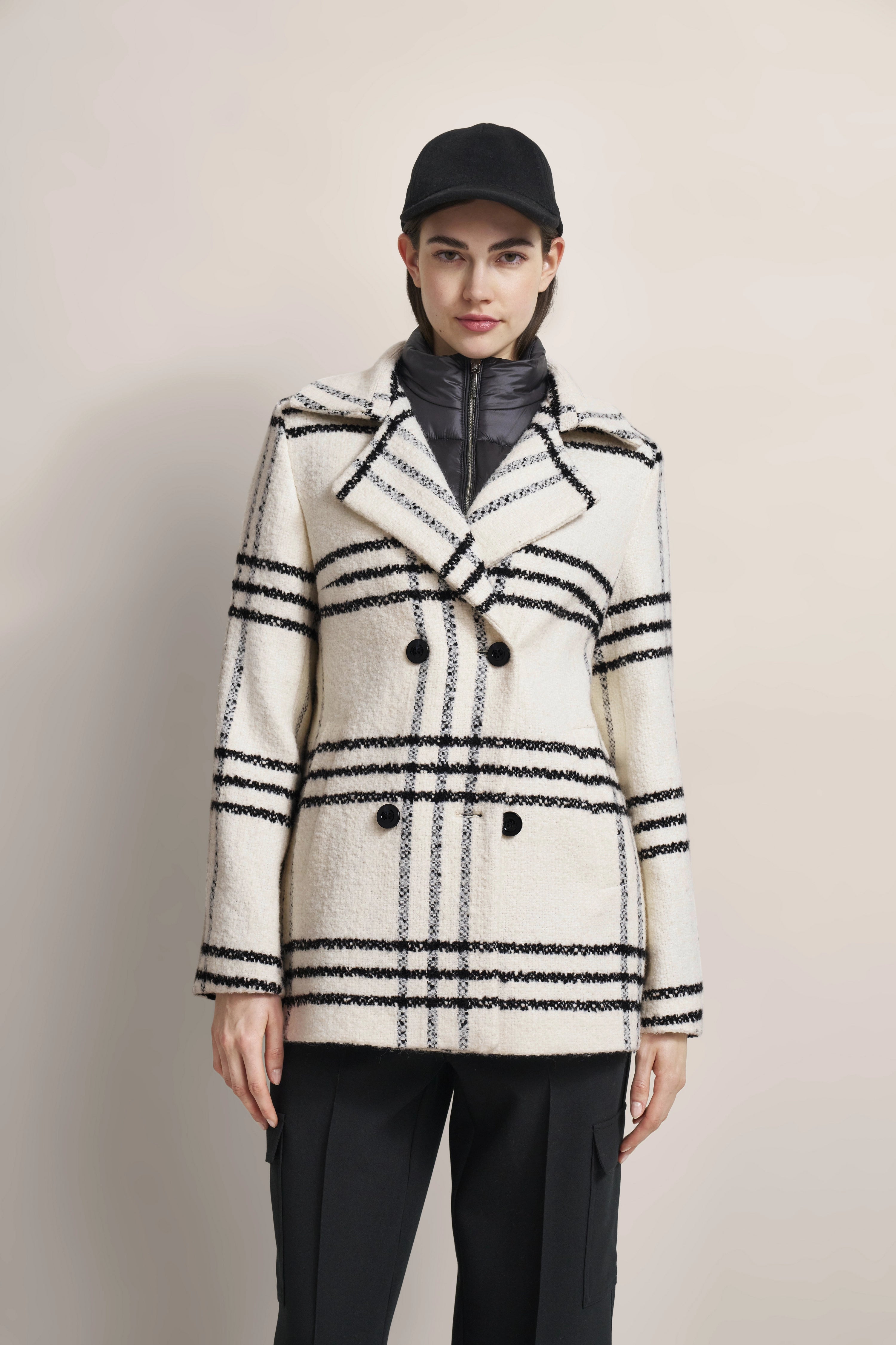 Model in Schwarz-Weiß kariertem bugatti-Mantel und schwarzer Hose, frontal stehend.