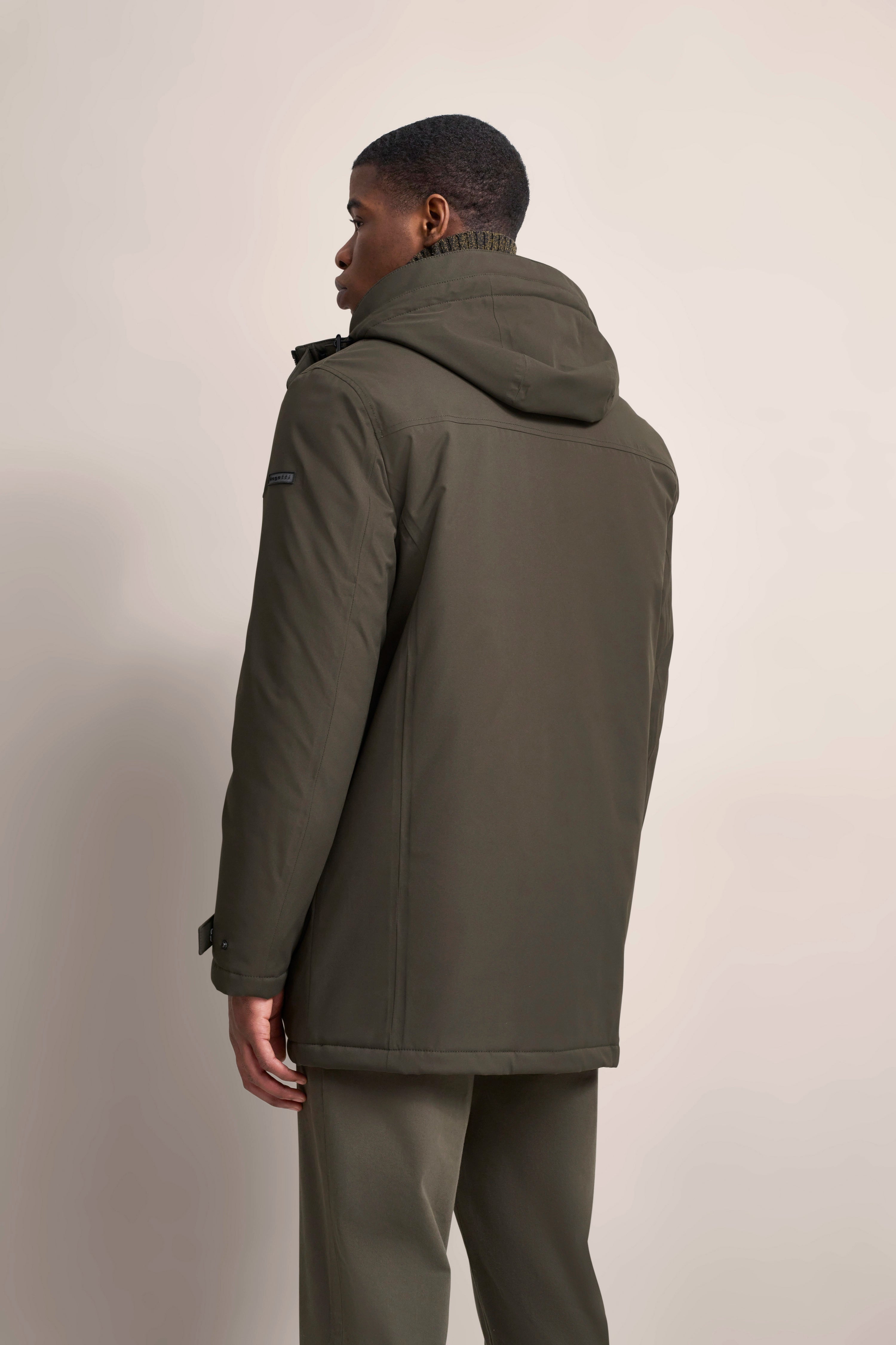 Model trägt olivgrünen bugatti Parka, Rückansicht, entspannte Pose.