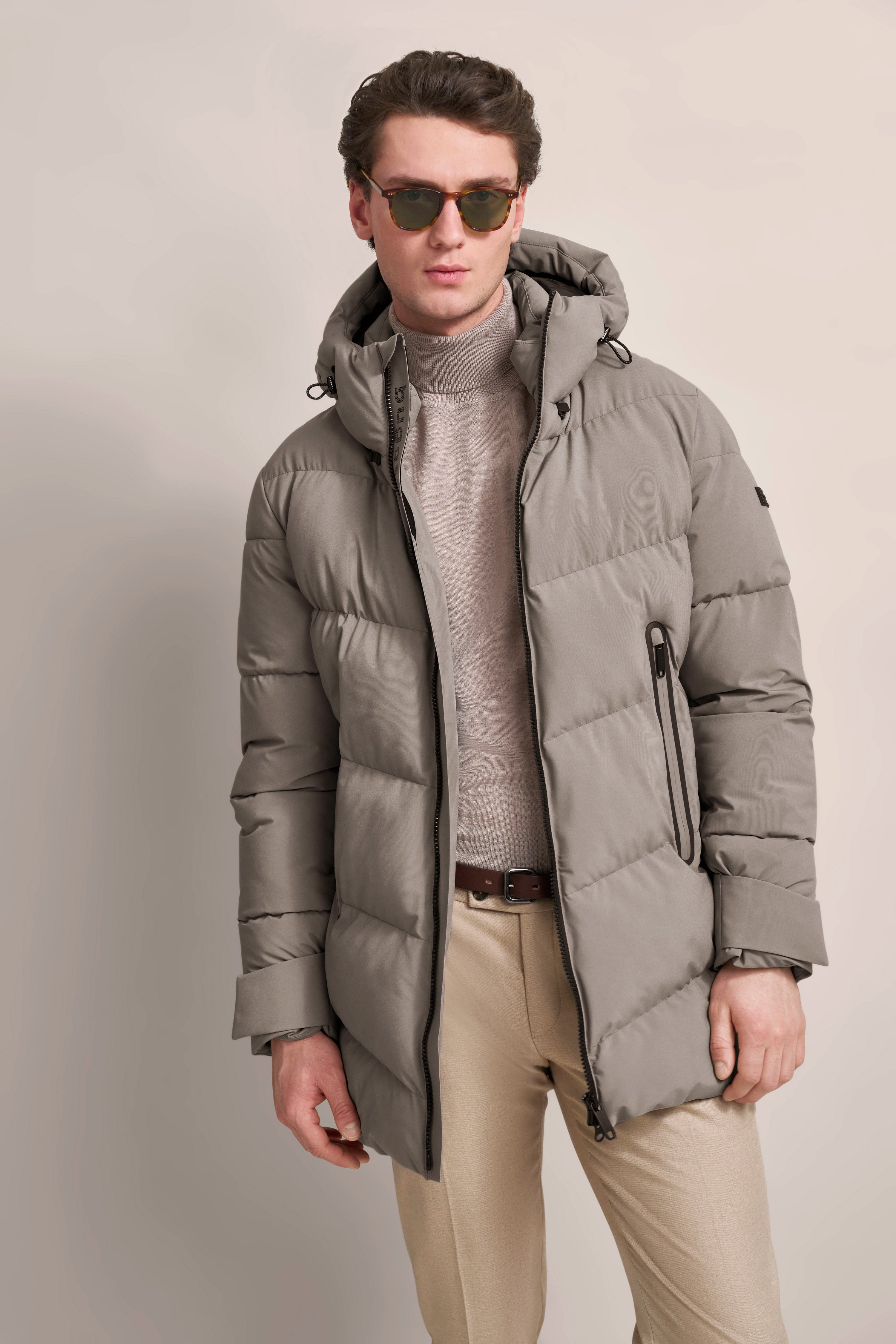 Gray bugatti down jacket, beige turtleneck, beige pants, model in relaxed pose.