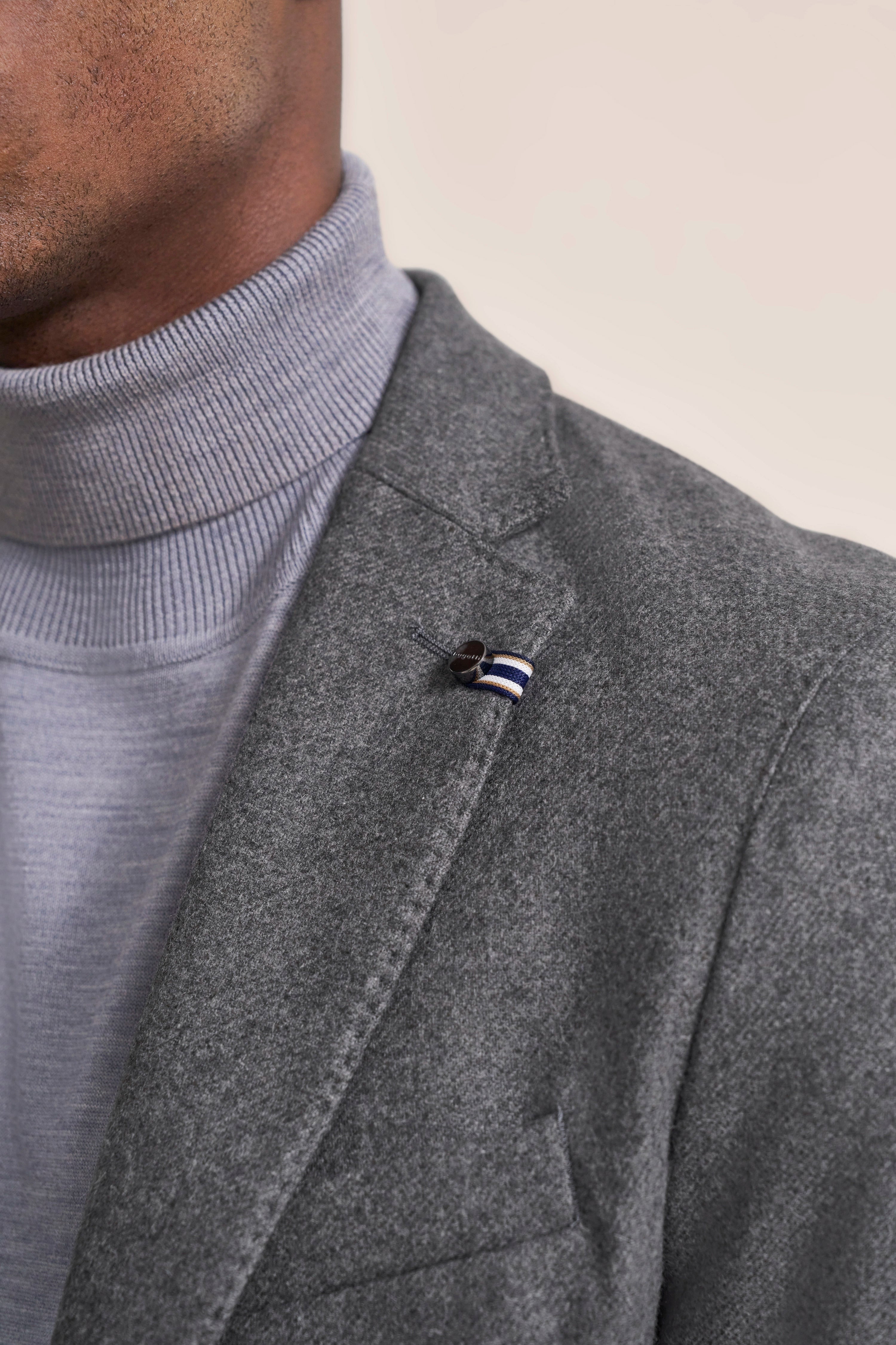 Grauer bugatti Blazer mit blau-weißem Akzent. Kombiniert mit grauem Rollkragenpullover. Büstenbild.