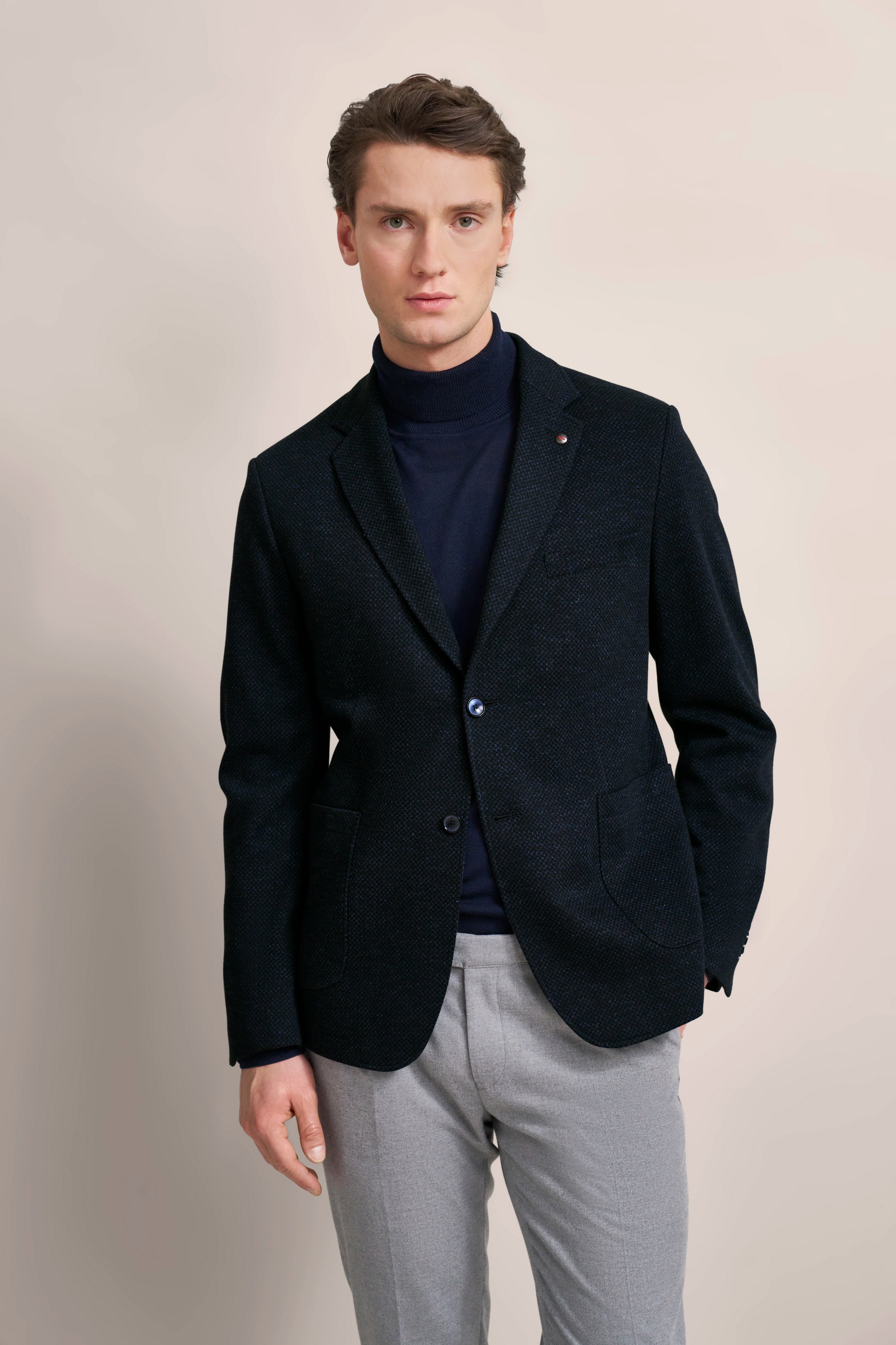 Dunkler Blazer, blauer Rollkragen, graue Hose, Modelbild stehend, bugatti Stil.
