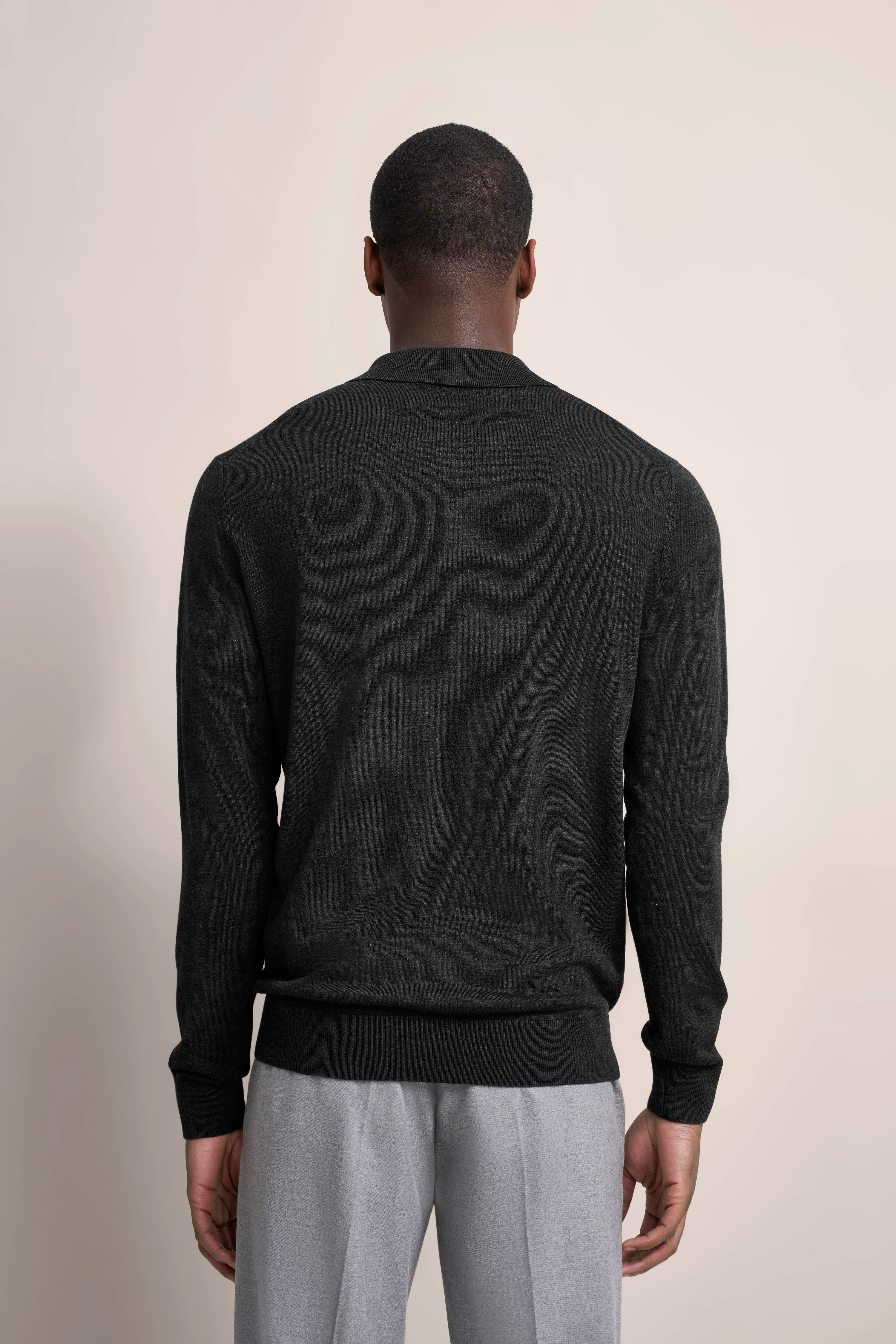 Rear view of model in black bugatti sweater and grey pants, casual pose.