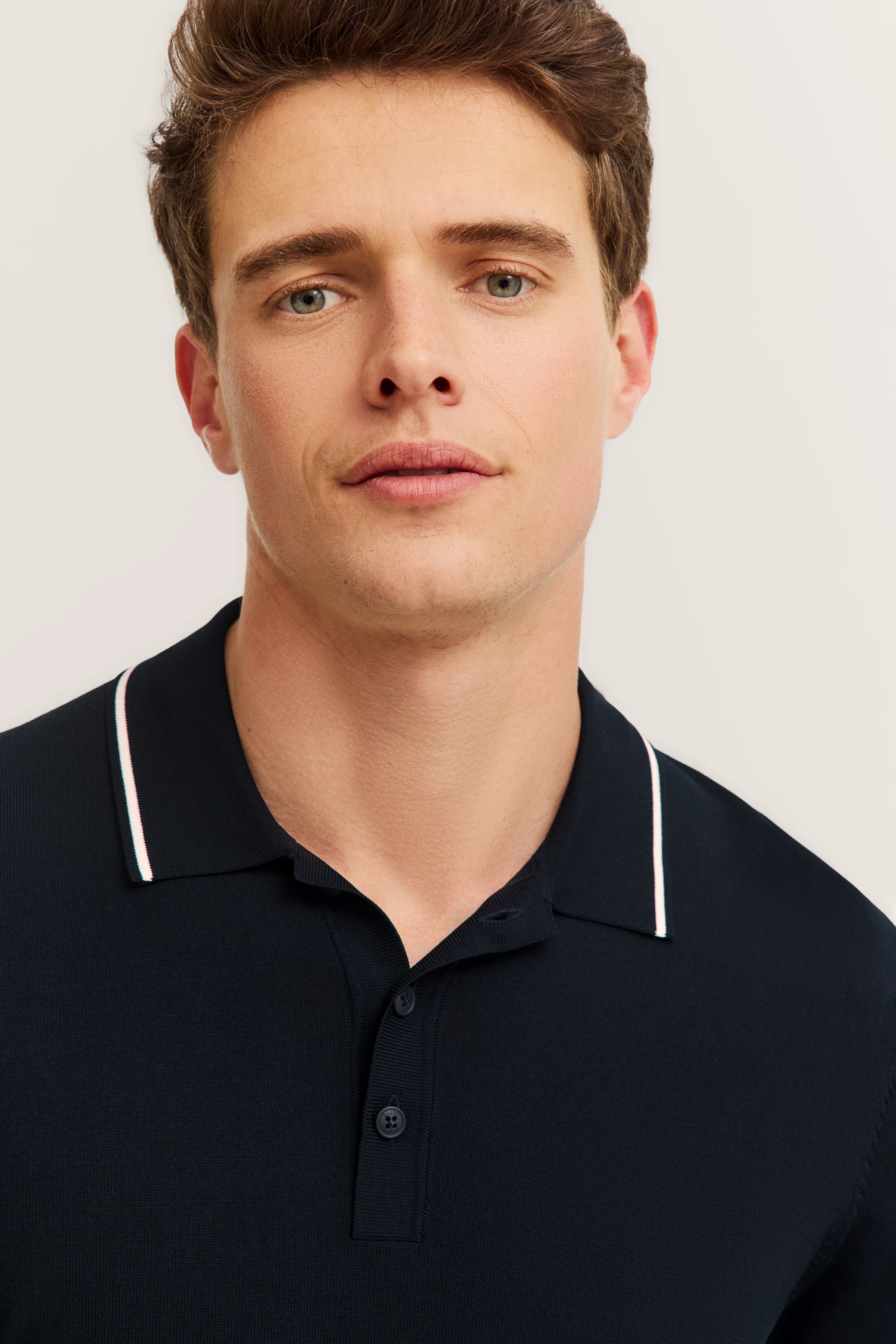Büstenbild mit dunkelblauem bugatti Polo, weißer Kragenrand, elegante Details.