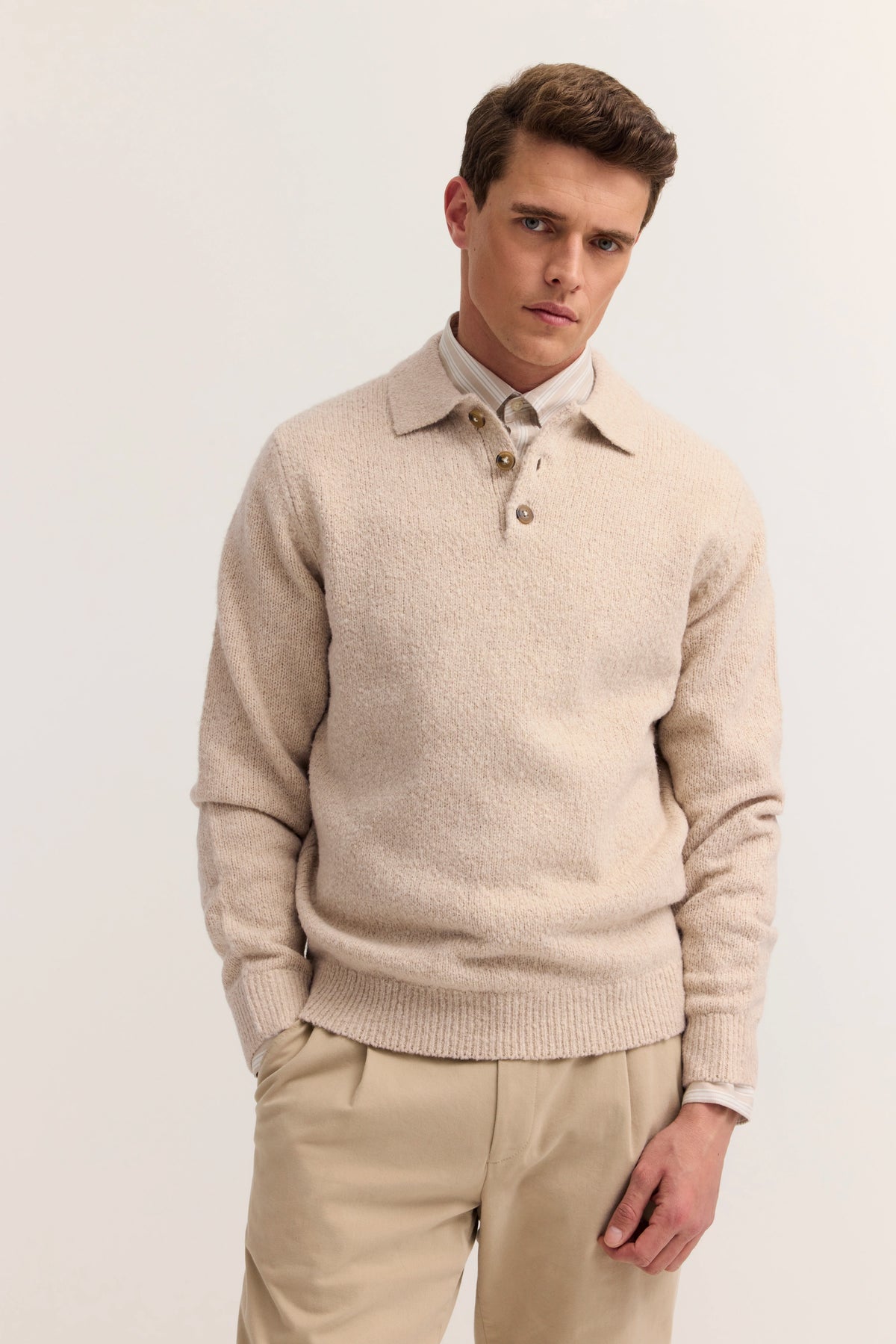 Beige Pullover und Hose, Model posiert mit leicht geneigtem Kopf, bugatti Stil.