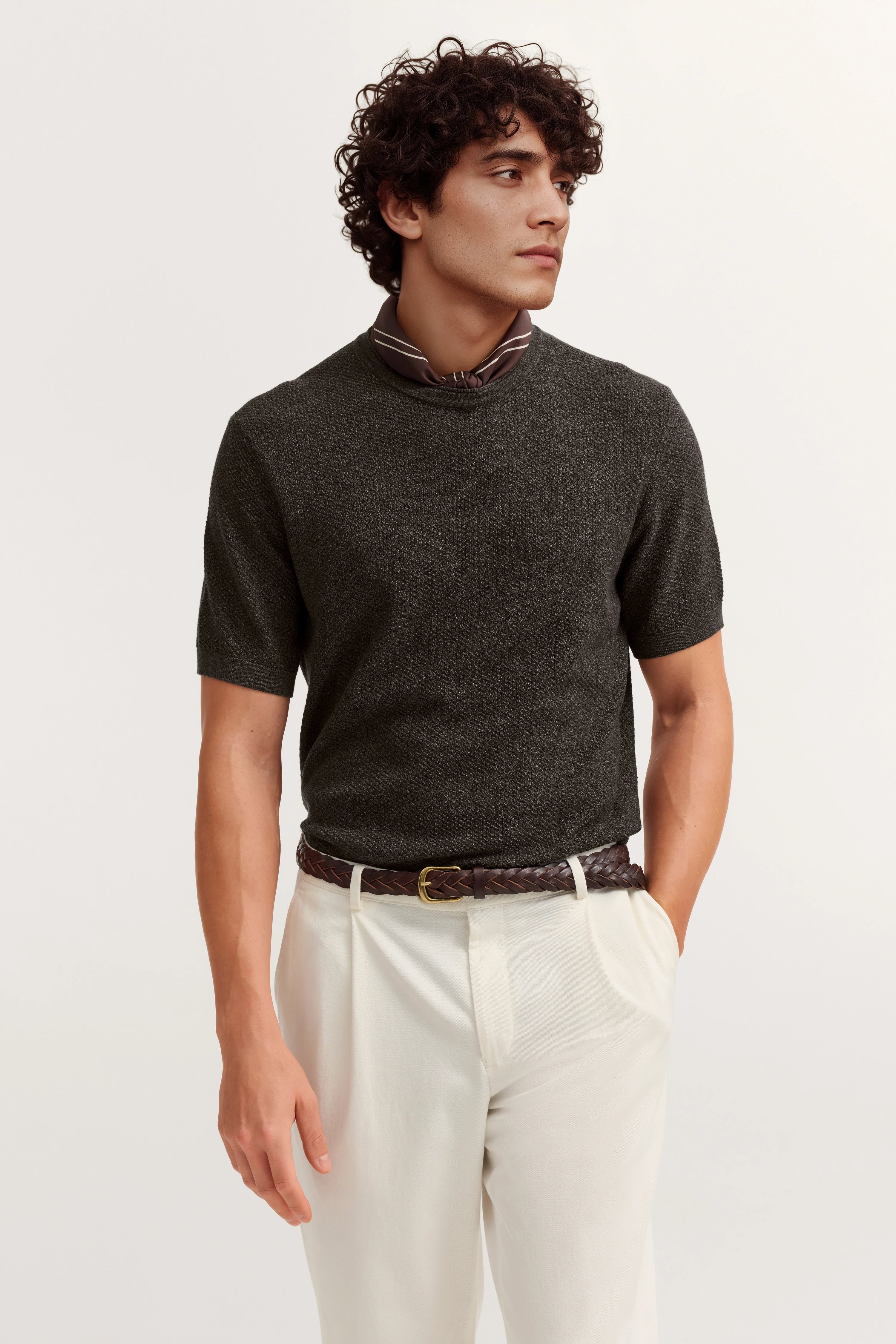 Model in dunkelgrauem Pullover und cremeweißer Hose, Posing lässig mit Hand in der Tasche.