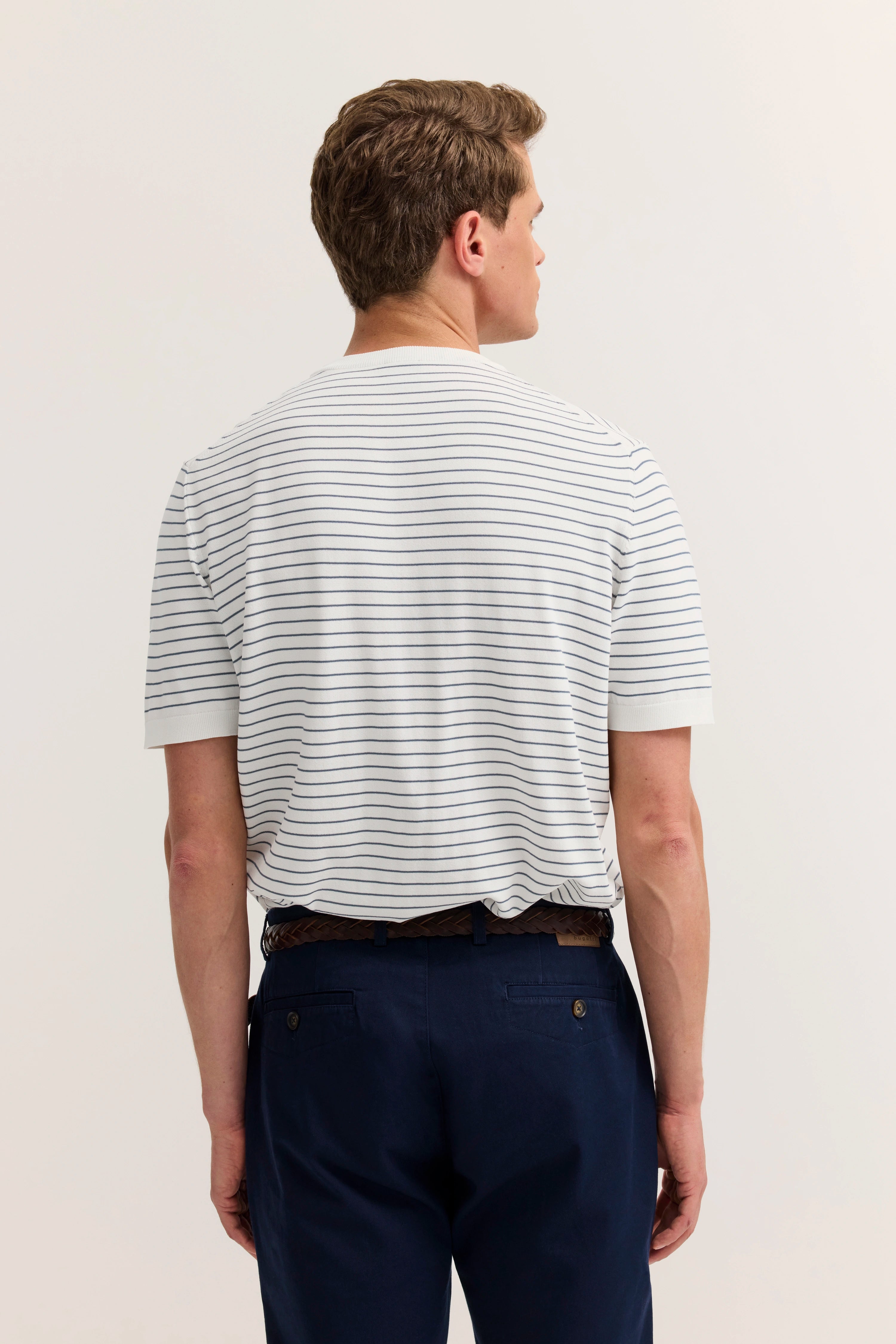 Hinteransicht Model in gestreiftem T-Shirt und blauer Hose, legeres Posing.