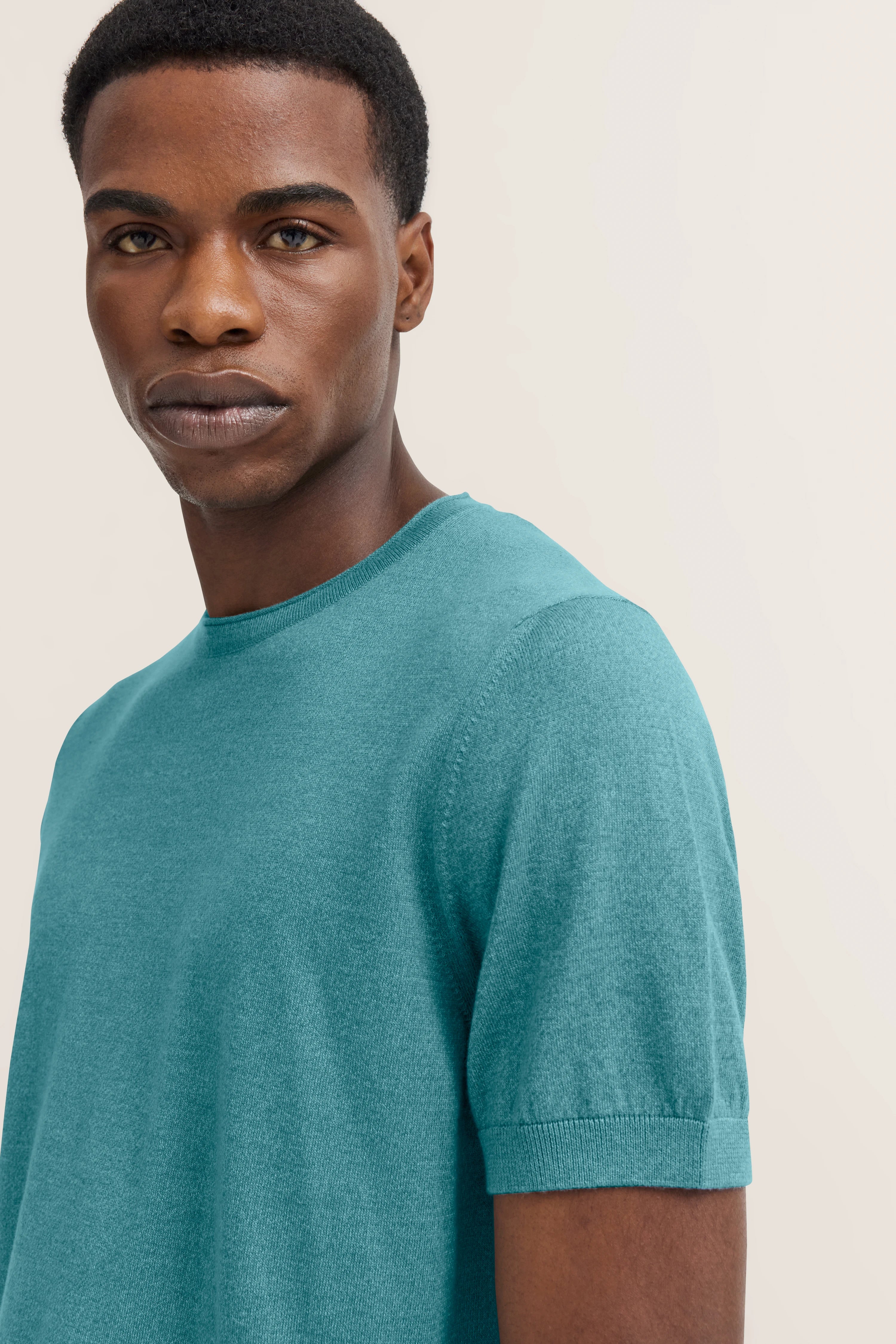 Bust shot of model in turquoise bugatti T-shirt, relaxed pose.