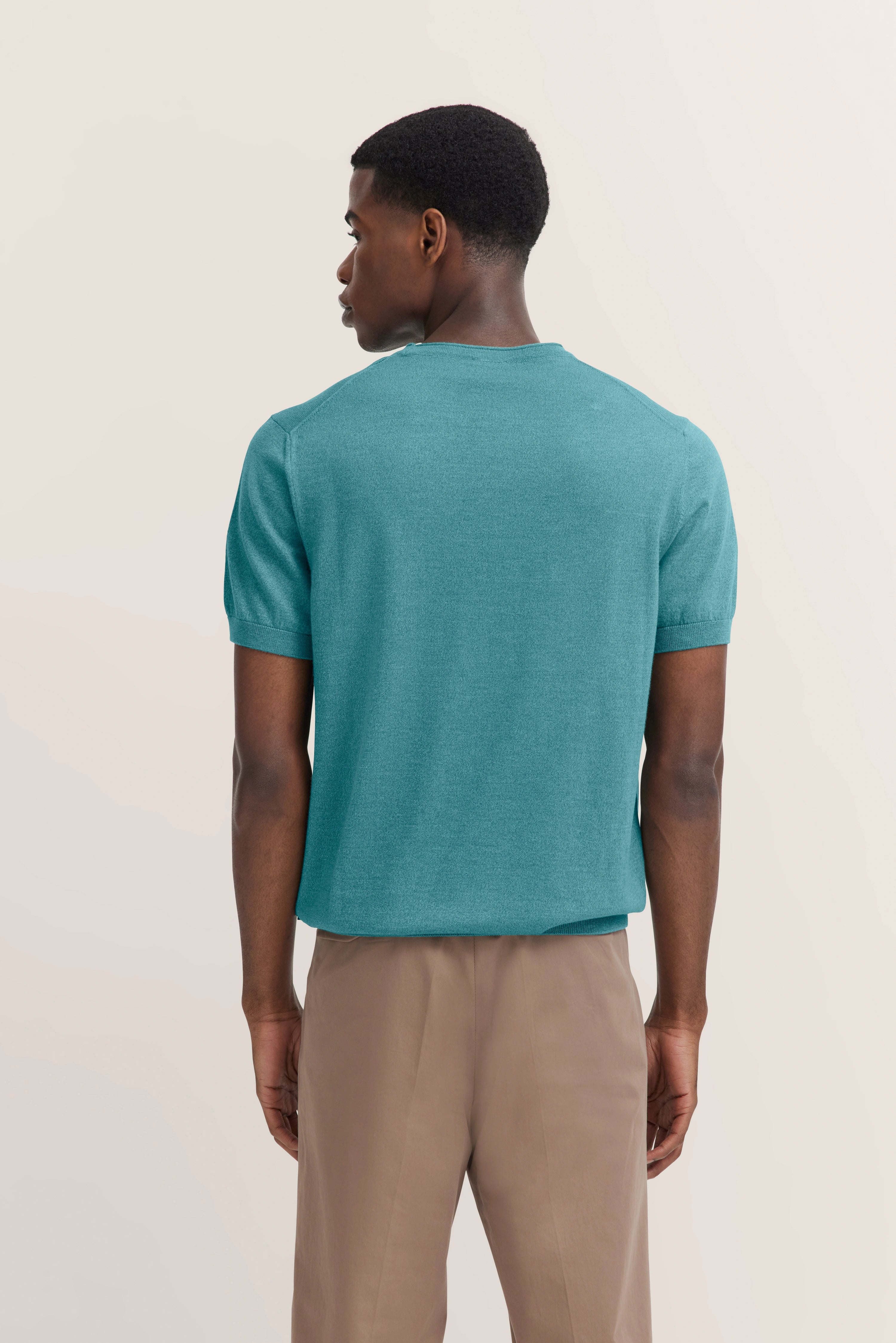Modelbild, Rückansicht: türkisblauer bugatti Pullover, beigefarbene Hose.