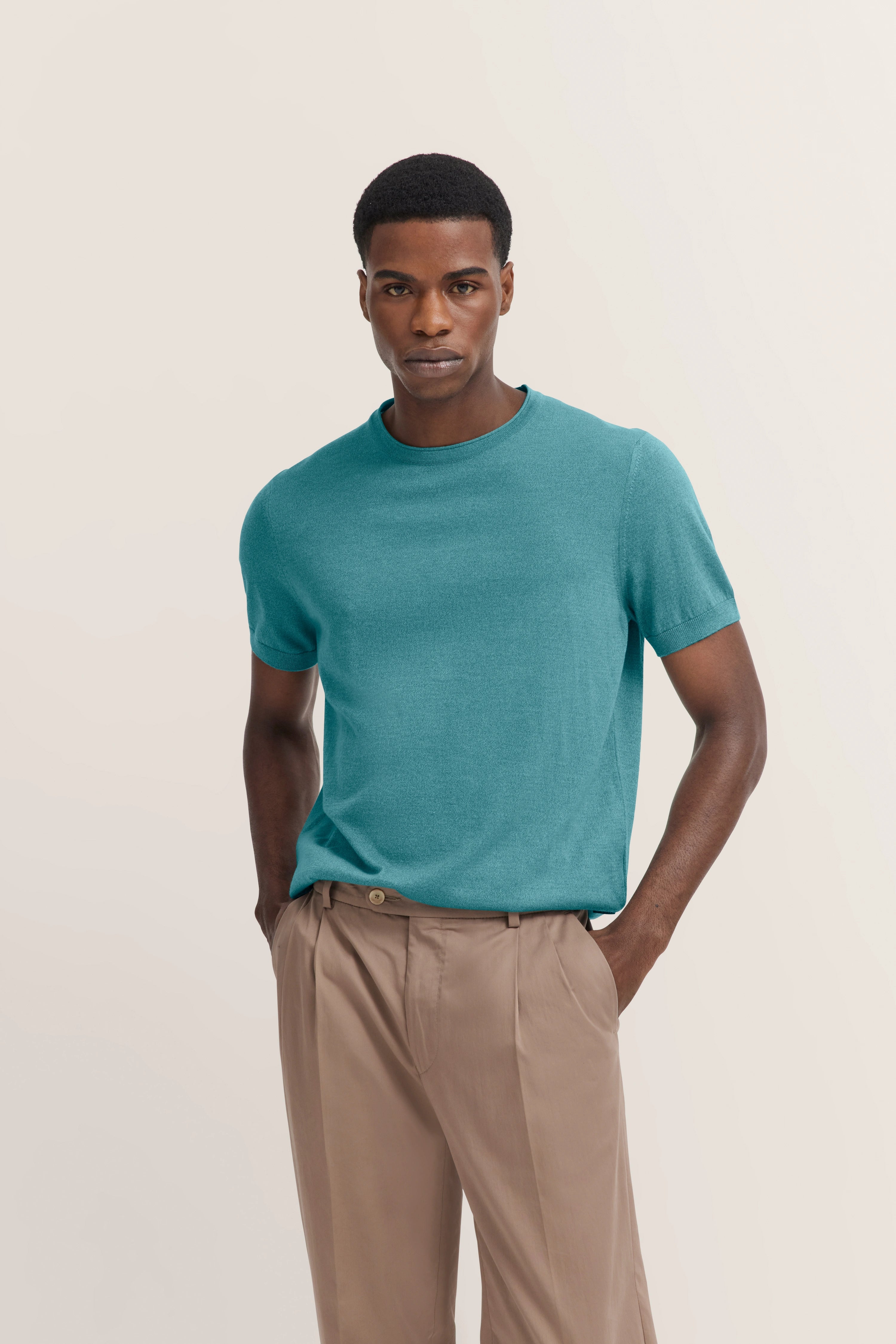 Modelbild: türkisfarbenes T-Shirt, beige Hose, lässige Pose, bugatti Stil.