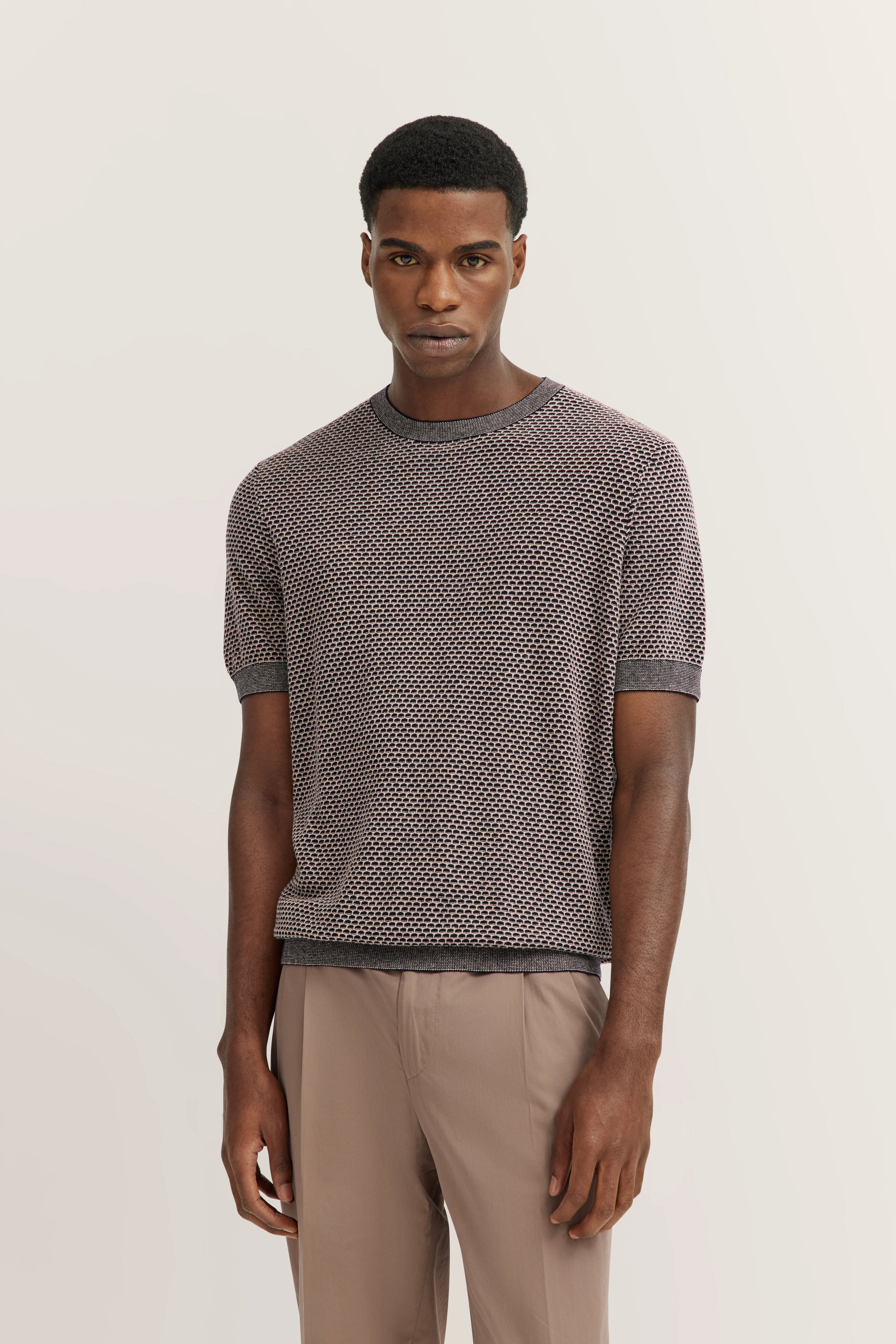 bugatti modelbeeld: man draagt grijs/beige T-shirt met patroon, ontspannen houding.