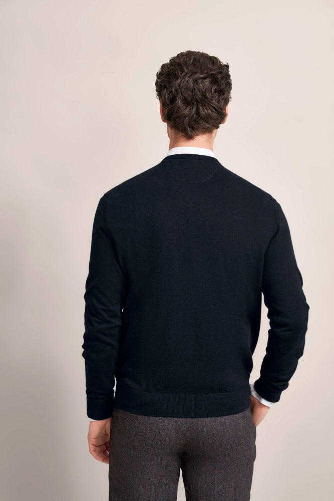 Bust of a man in a dark blue bugatti sweater and gray pants, back view.