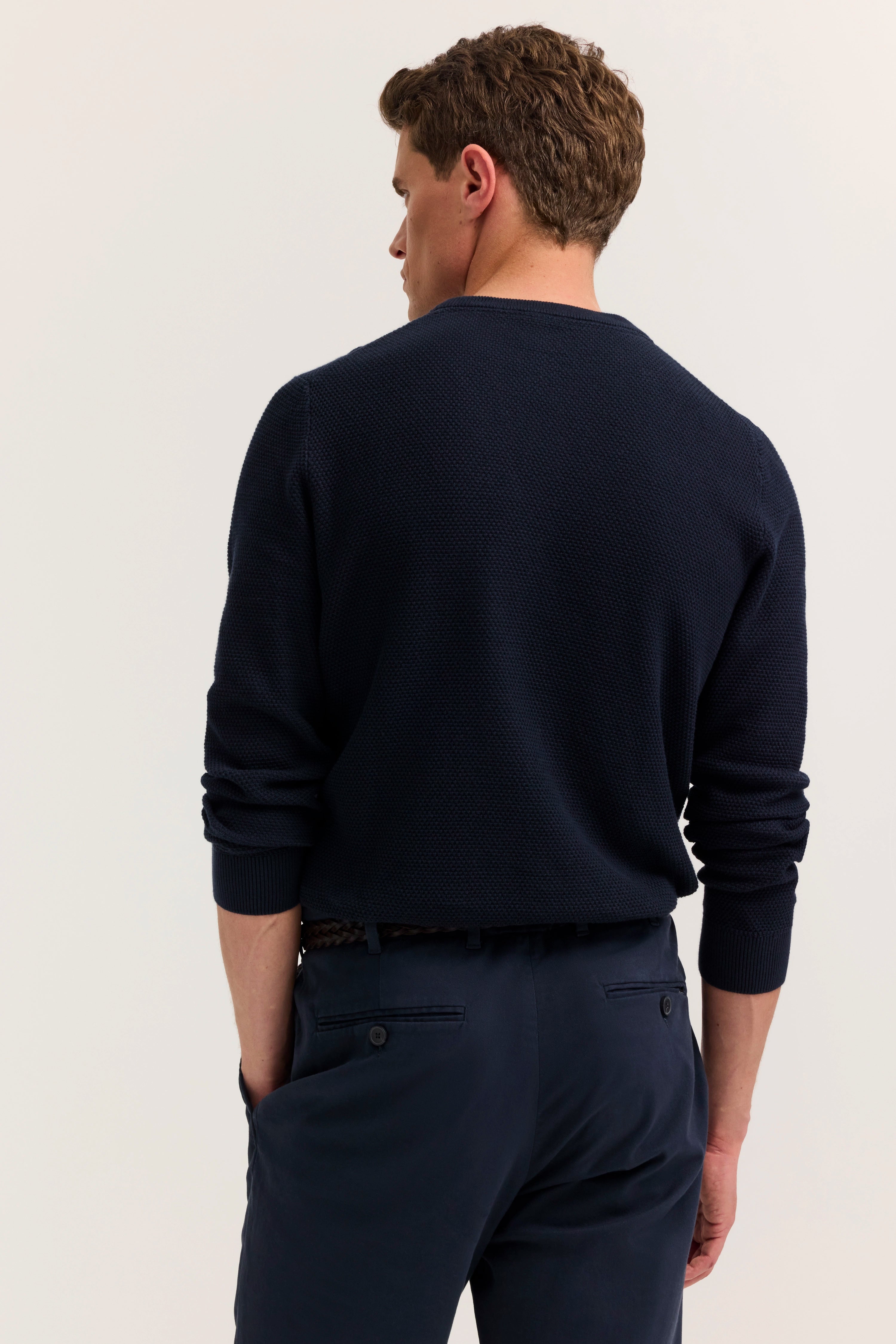 Navyblauer Pullover und Hose von bugatti, Model von hinten, lässige Haltung.