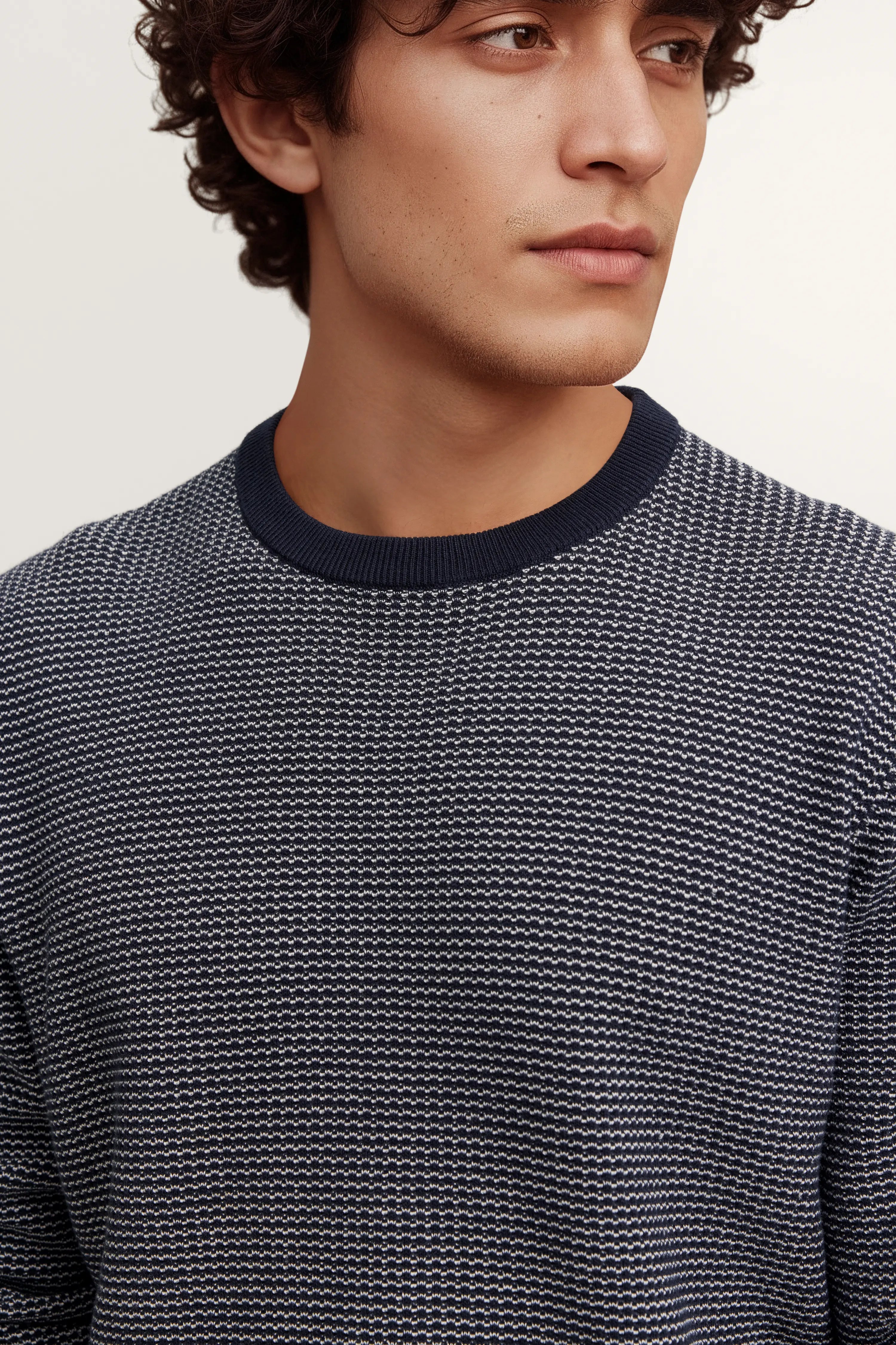 Navy-weiß gemusterter bugatti Pullover auf Model, legeres Posing, Detailaufnahme.