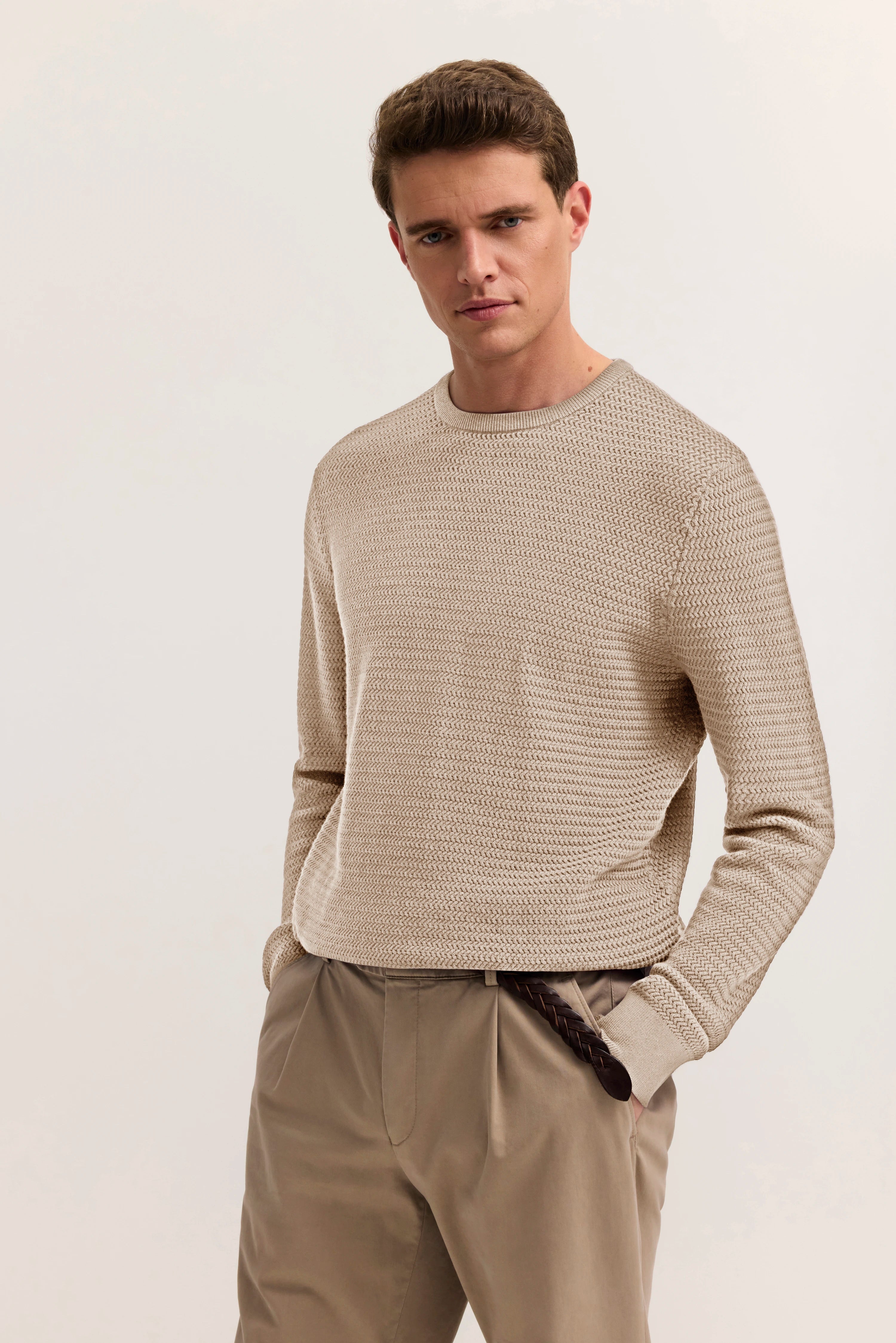 Beiges Strickpullover und beige Hose, legeres Modelbild, Hände in Hosentaschen.