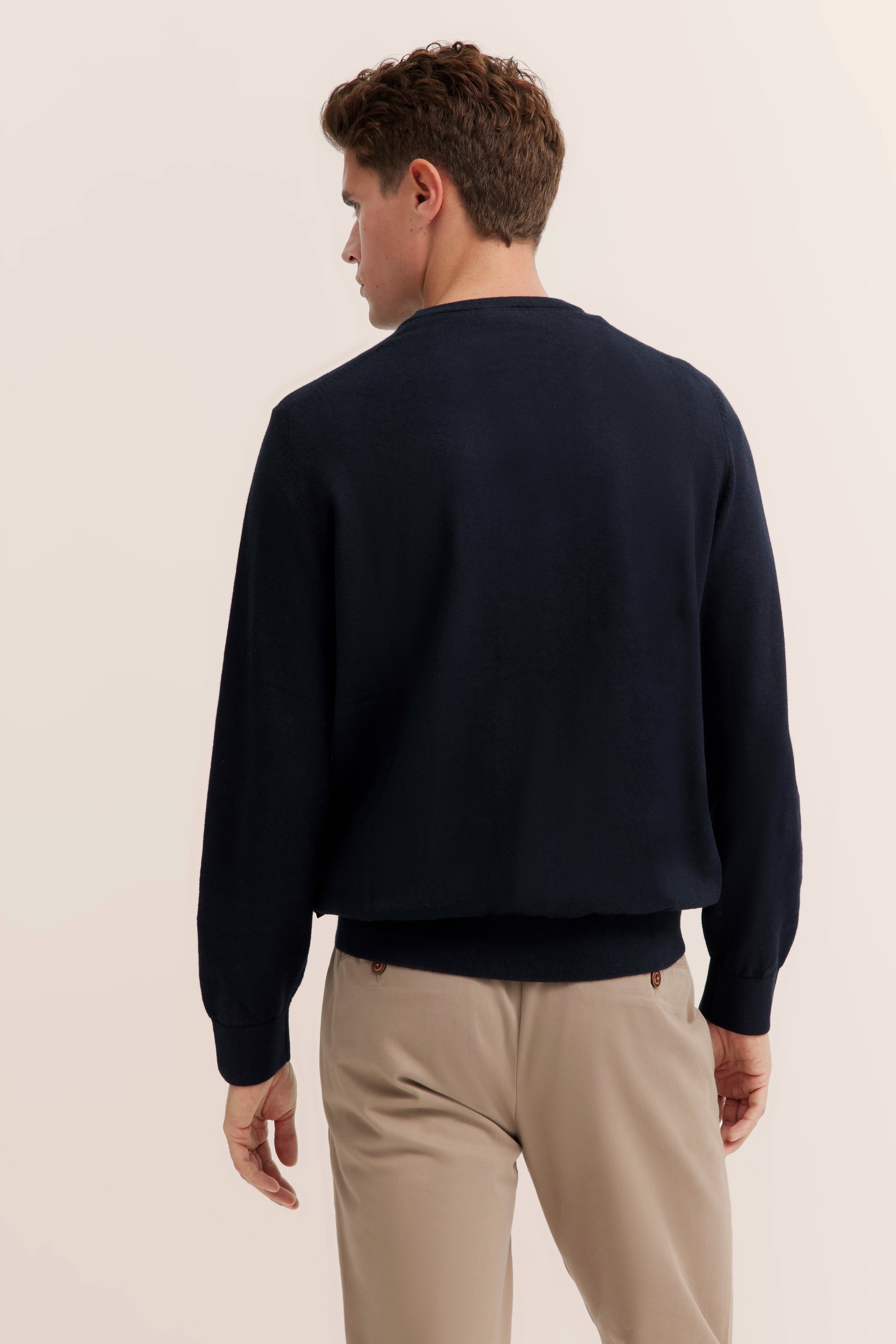 Navy sweater and beige chinos, model from behind, relaxed pose, bugatti style.