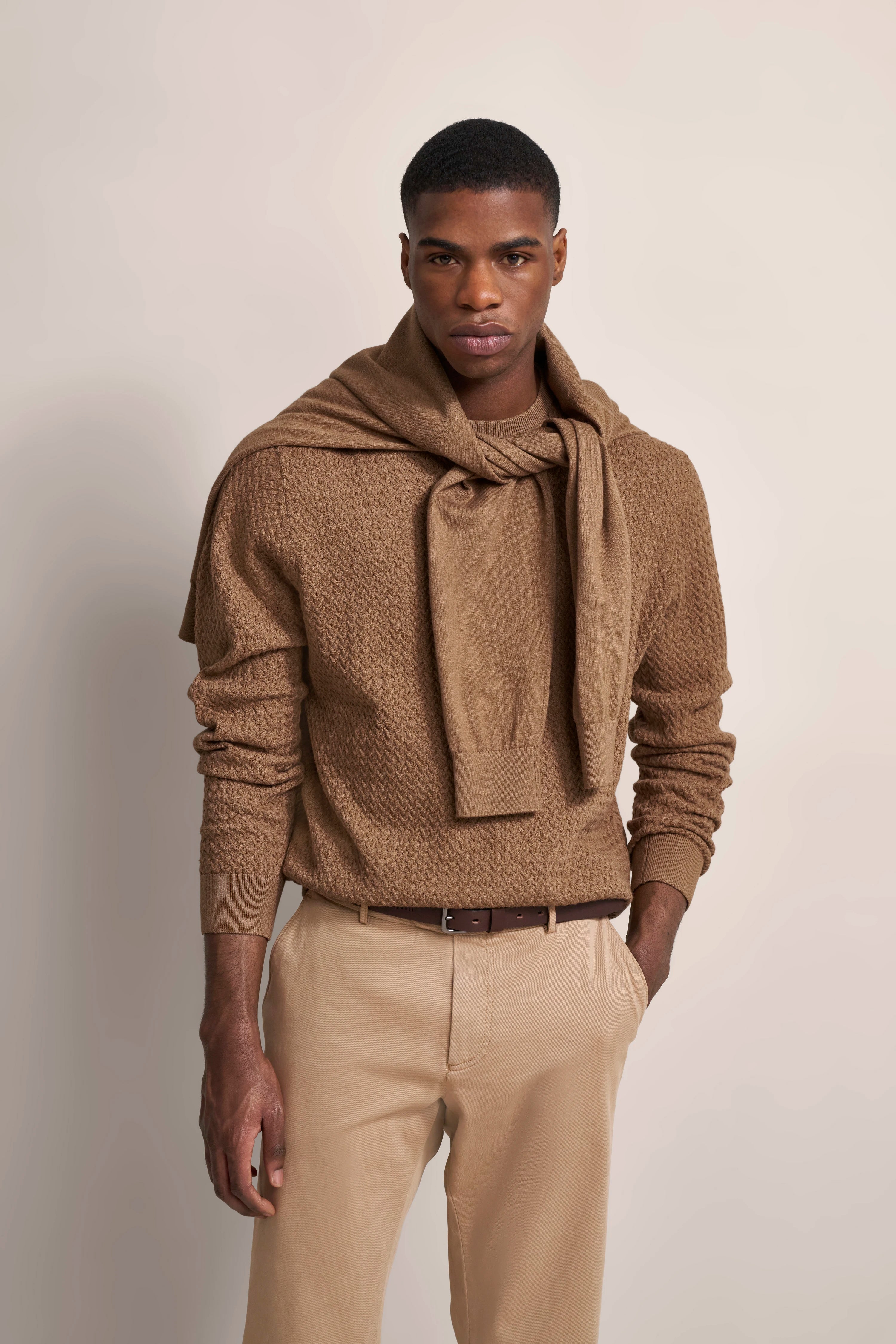 Bugatti Outfit: Brauner Pullover, umgebundener Schal, beige Hose, Modelbild, entspannte Haltung.