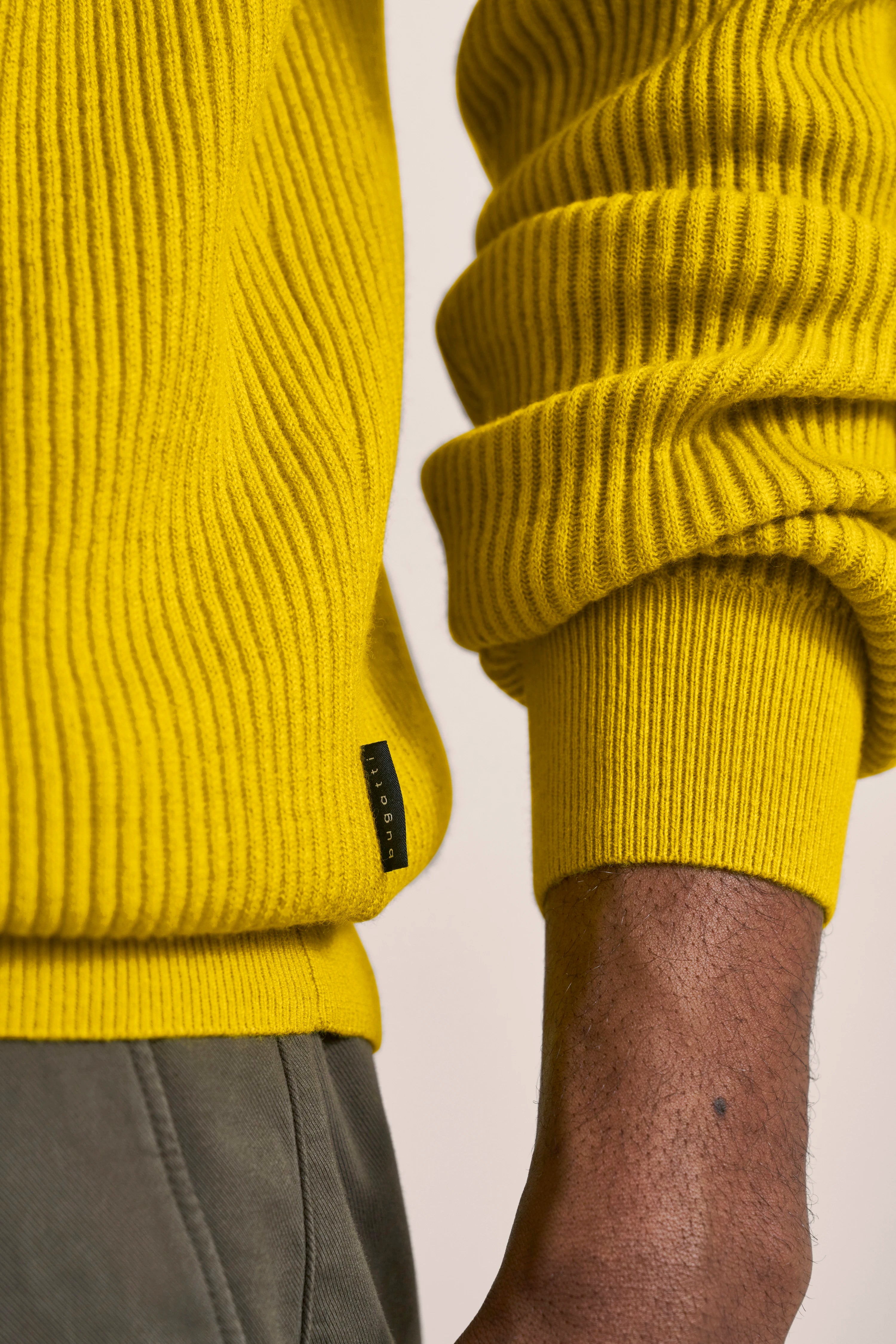 Yellow bugatti knit sweater close-up, casual wear with gray pants.