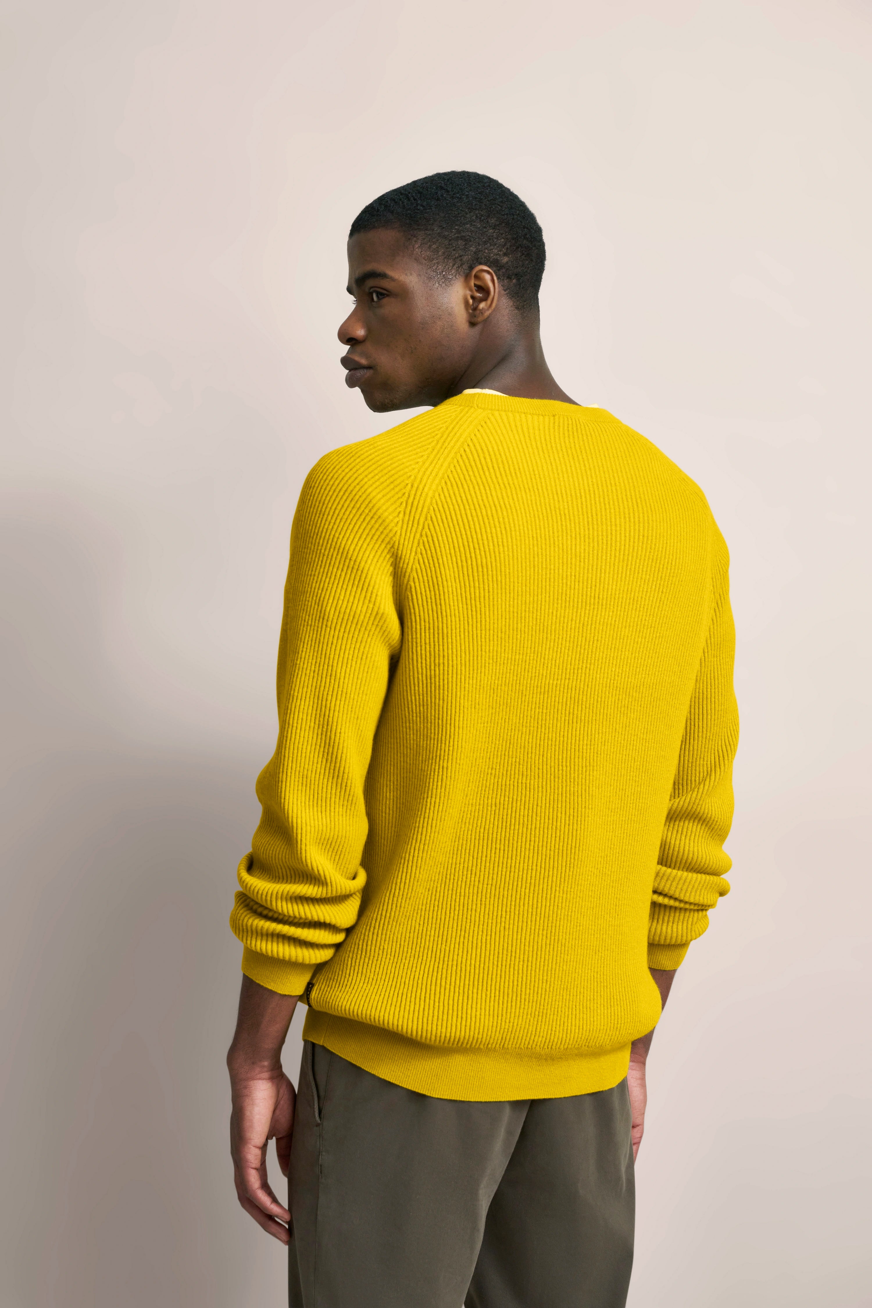 Yellow bugatti sweater, casually shown on model from back, paired with olive green pants.