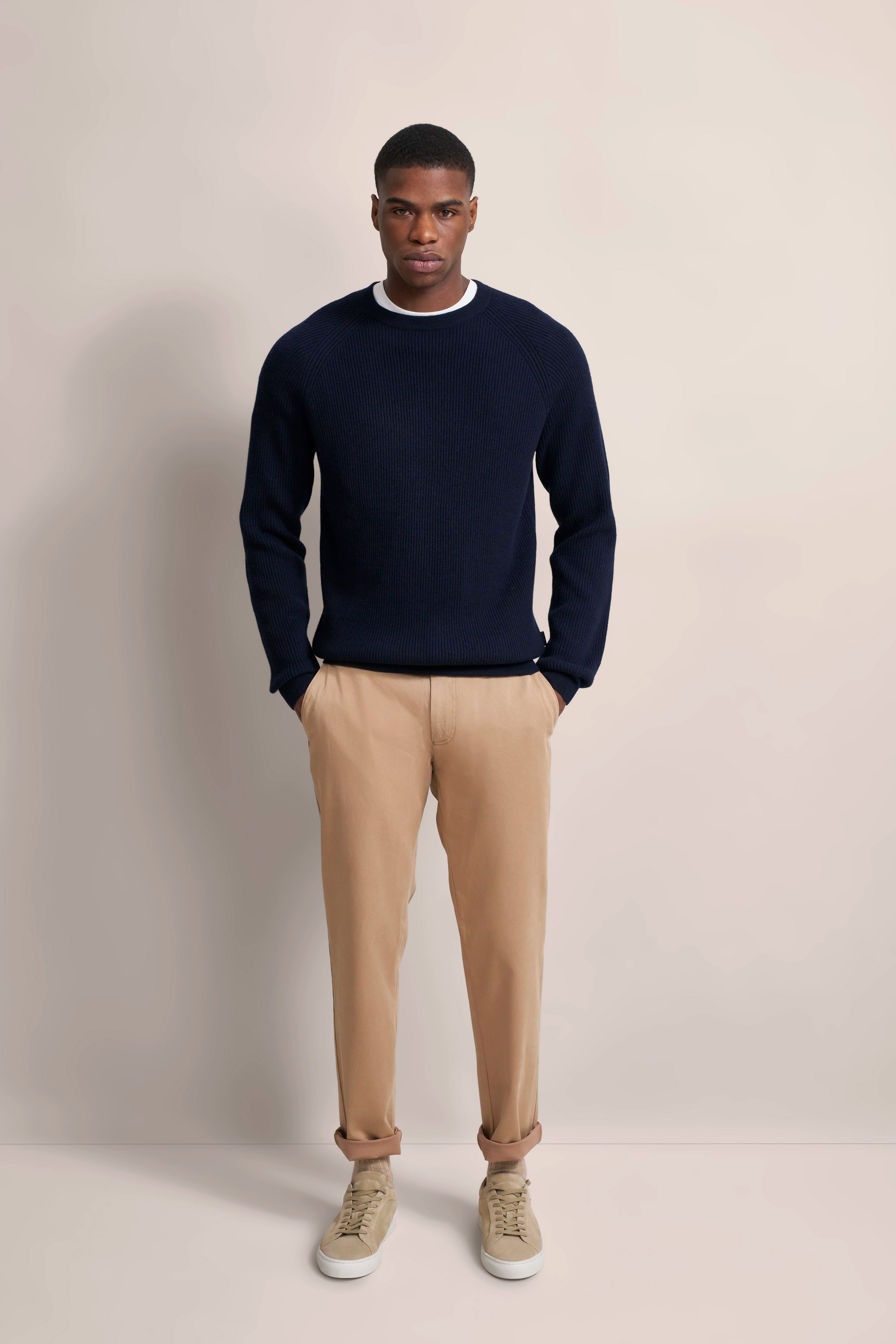 Navy Pullover und beige Chinos bei bugatti Modelbild, entspannter Stand.