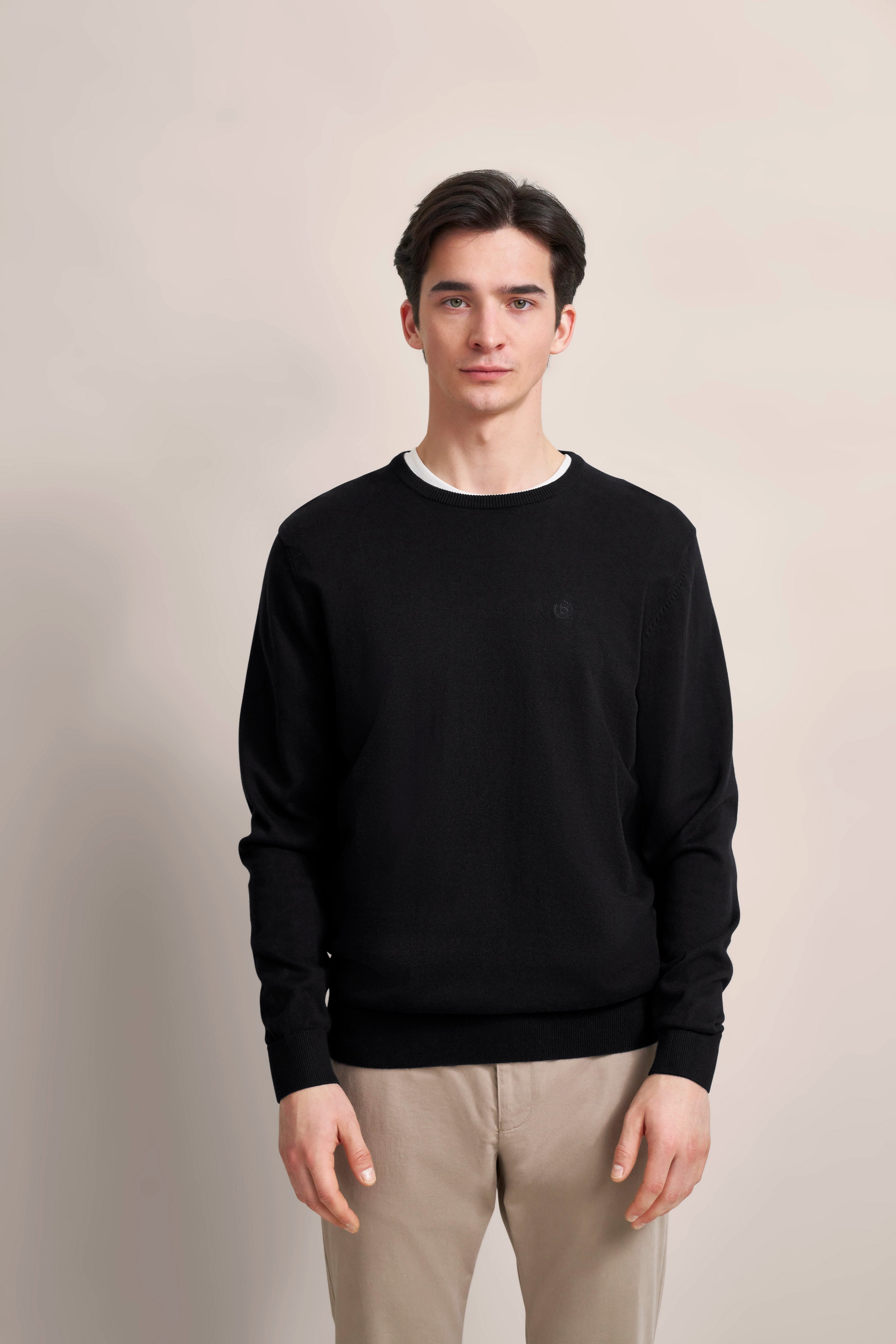 bugatti Modelbild, schwarzer Pullover, beige Hose, entspanntes Posing, eleganter Look.