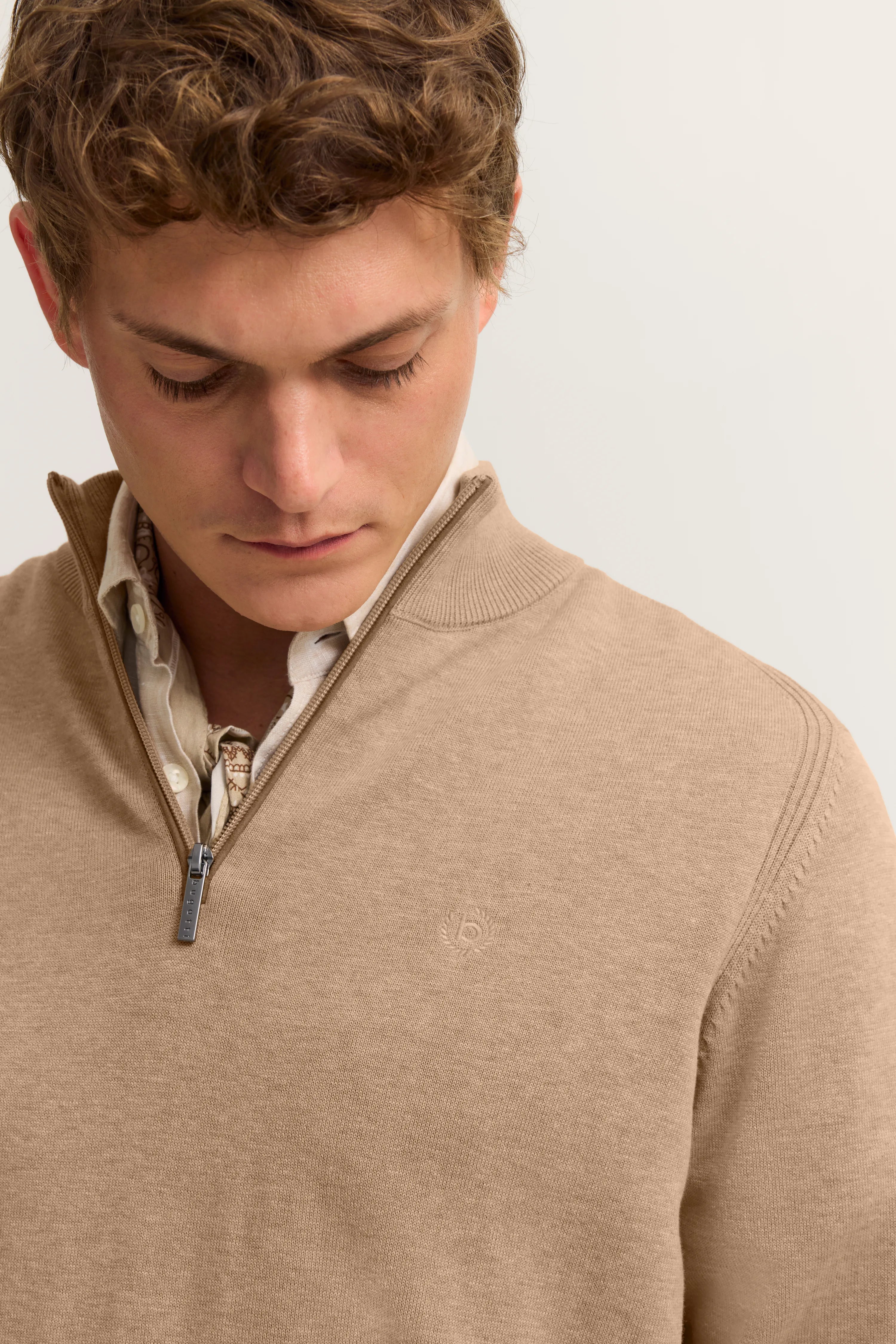 Beigefarbener bugatti Pullover mit Zipper, darunter weiß gemusterte Hemdbluse. Büstenbild.