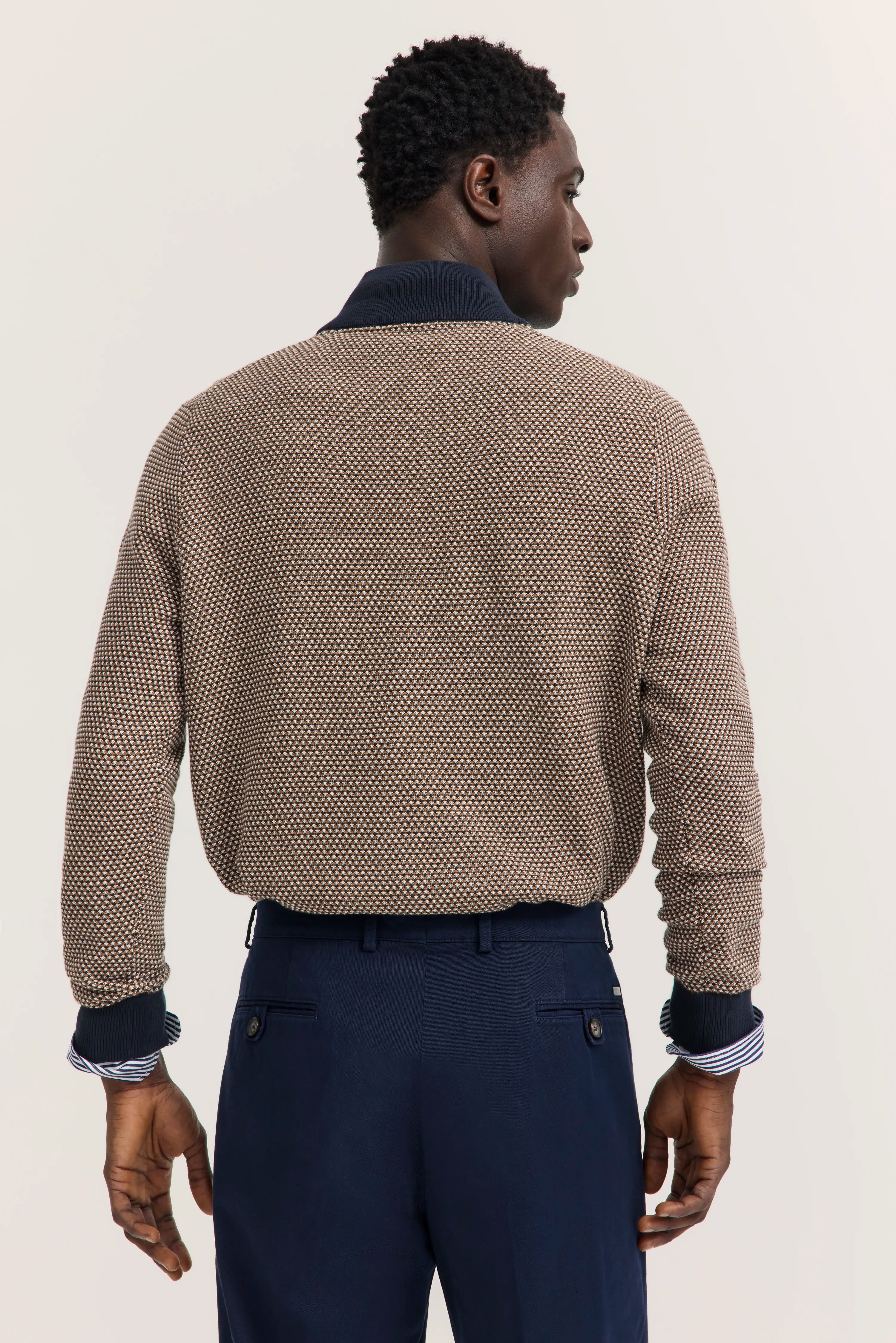 Modelbild mit Rückenansicht, trägt gemusterten Pullover in Braun und Dunkelblau mit blauen Hosen von bugatti.