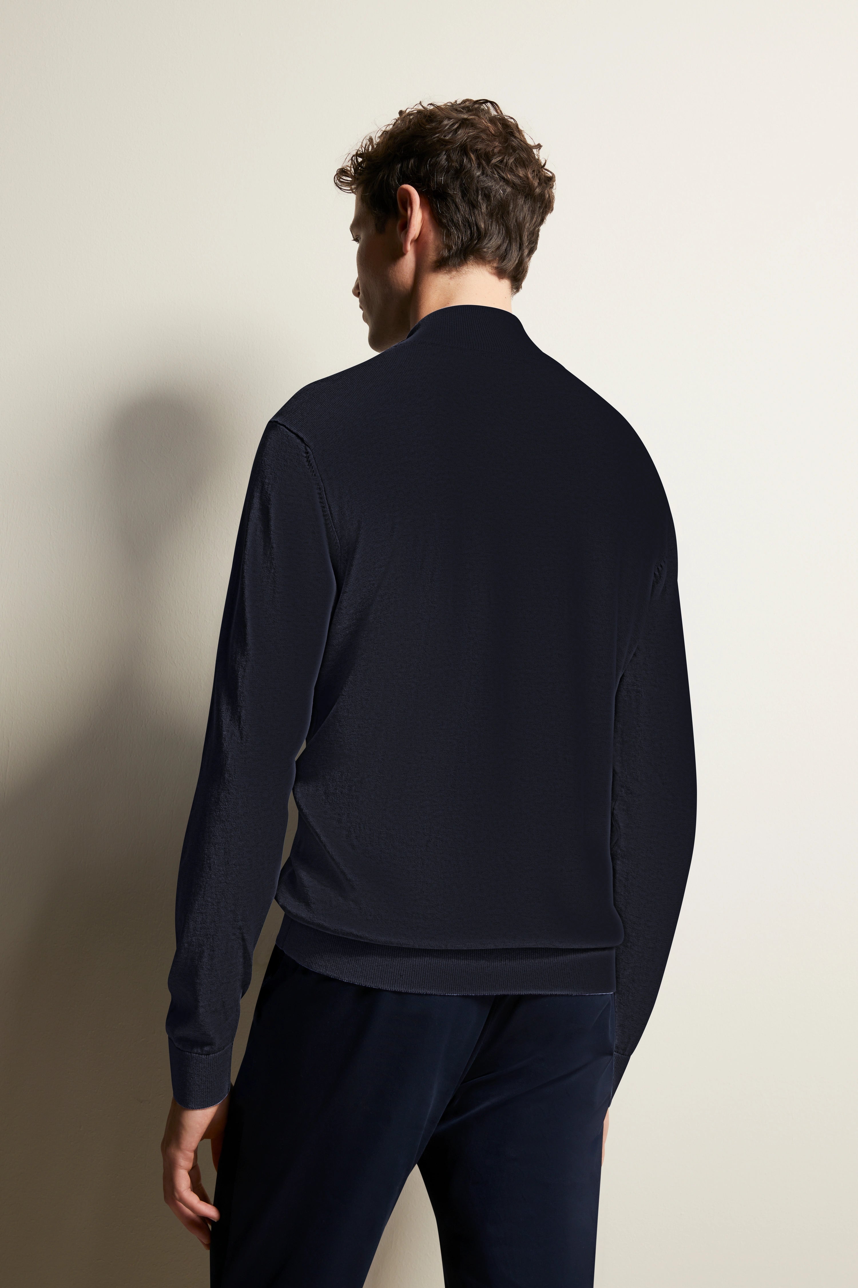 Model in dunklem Longsleeve und Hose von bugatti, Rückenansicht, lässiges Posing.