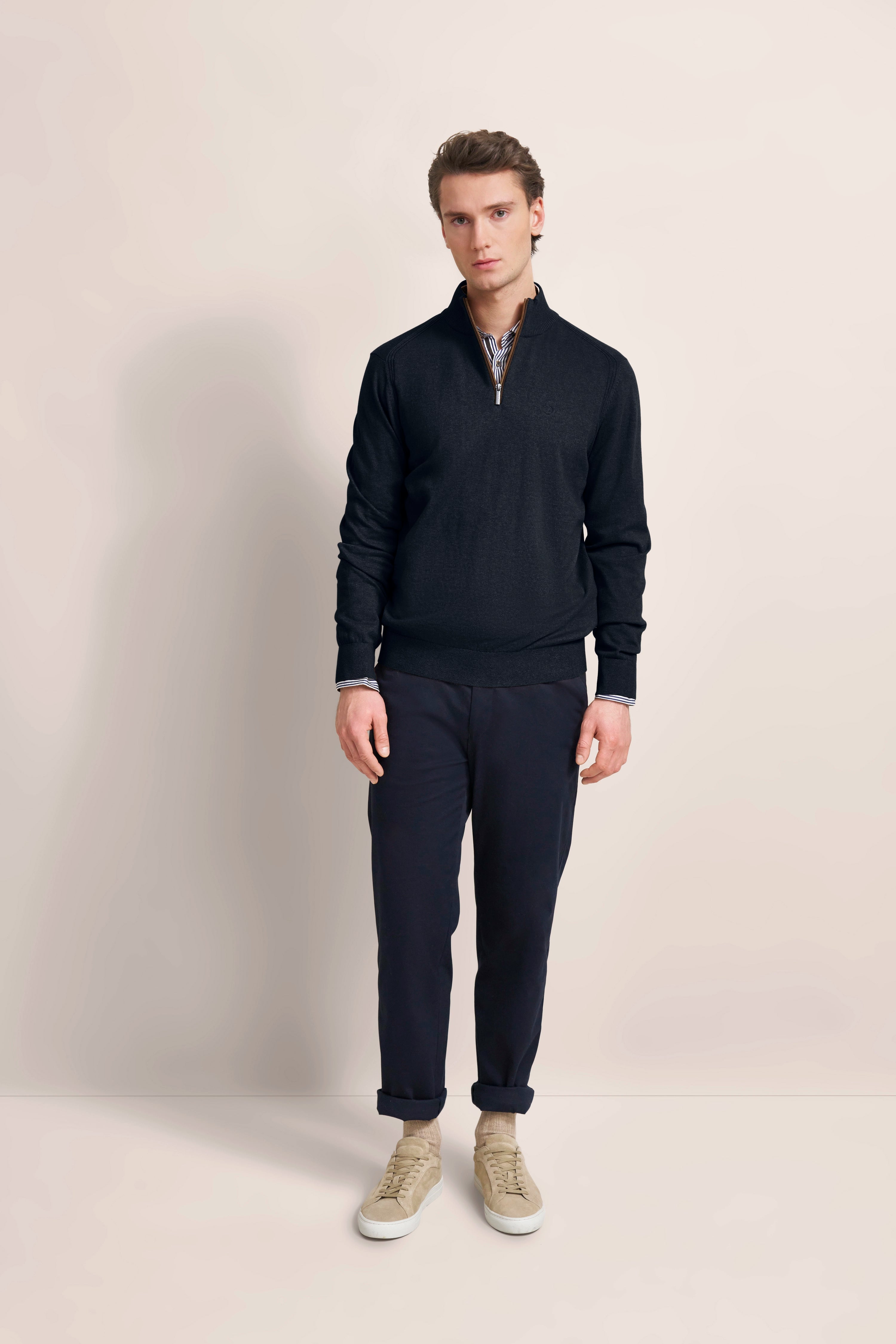 Model in schwarzem bugatti Pullover, dunkler Hose, beige Sneakers, relaxed stehend.