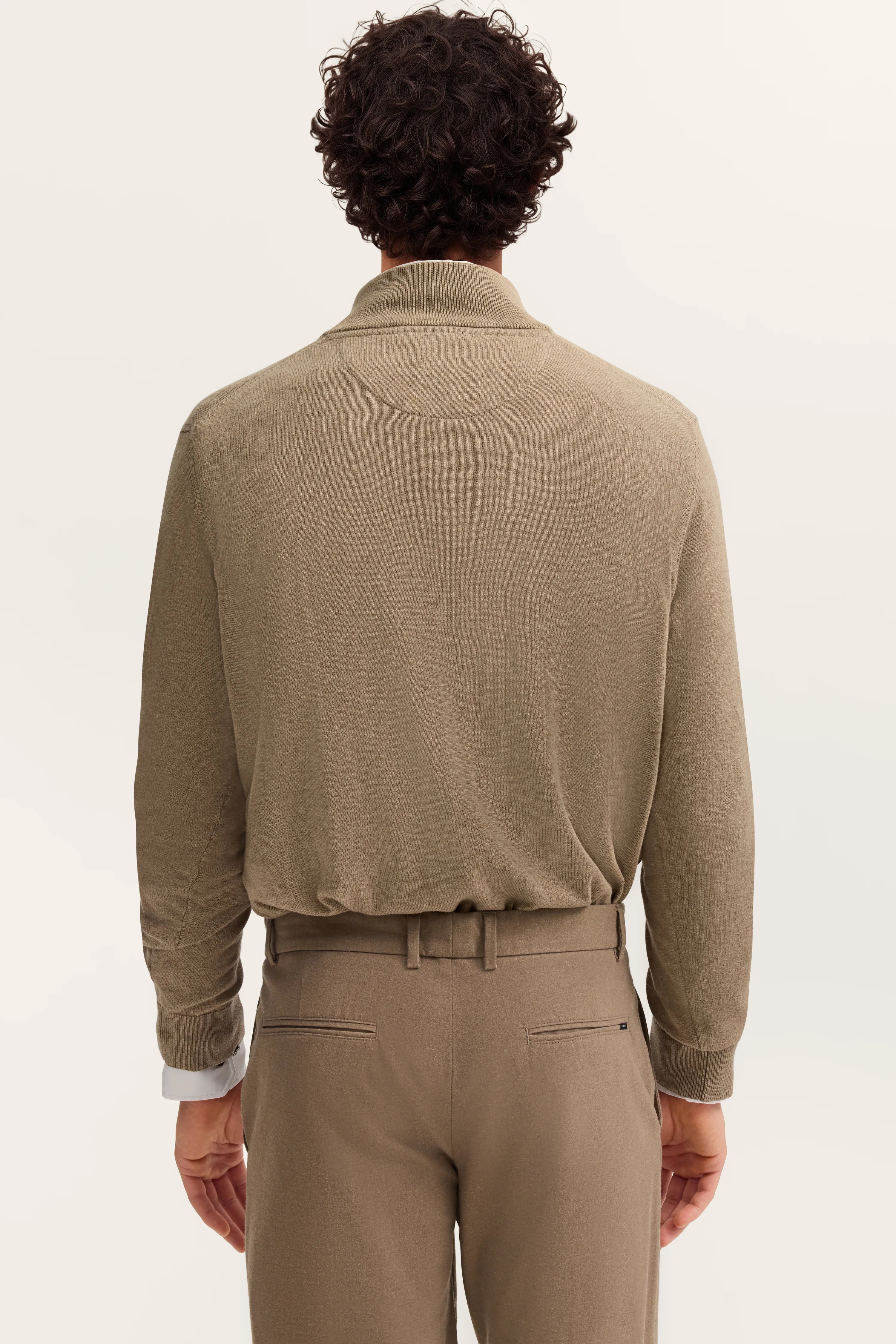 Männliches Model von hinten in beigem Pullover und Hose, legeres Styling, bugatti Mode.