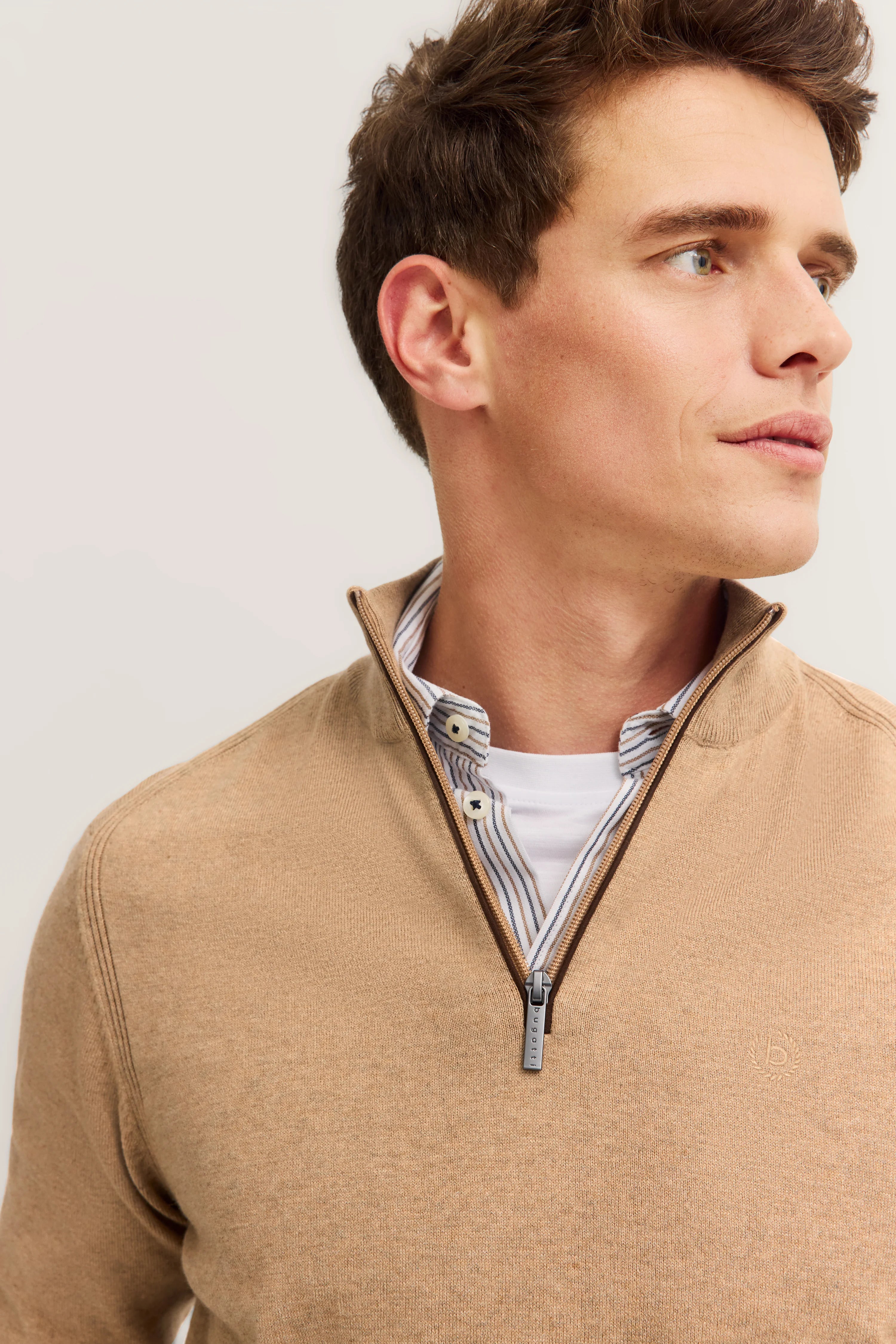 Beige bugatti Pullover mit Reißverschluss über gestreiftem Hemd, Modelbild, Kopf seitlich betrachtet.