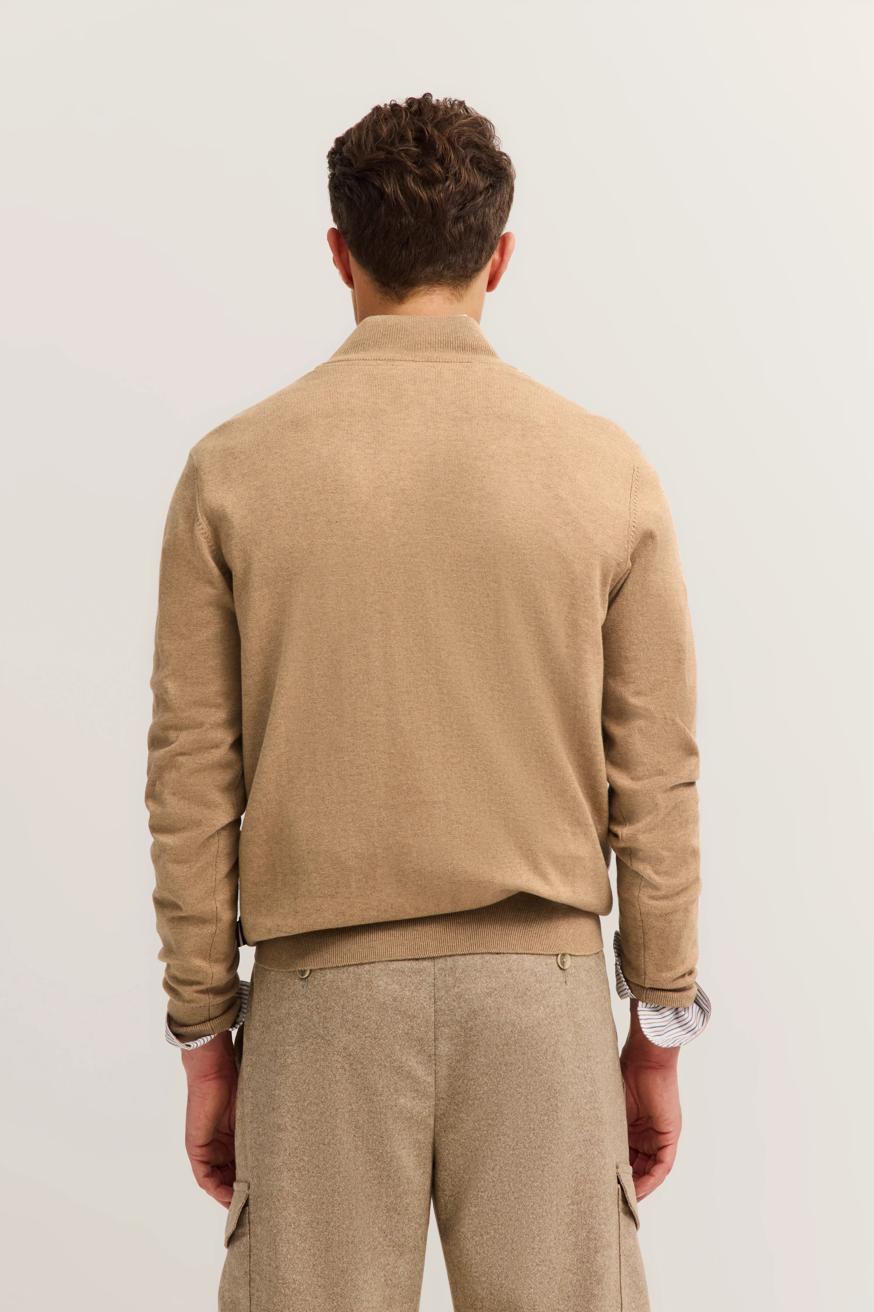 Beige bugatti Outfit, Rückansicht, leger mit langärmligem Oberteil und Cargohose, Model steht entspannt.